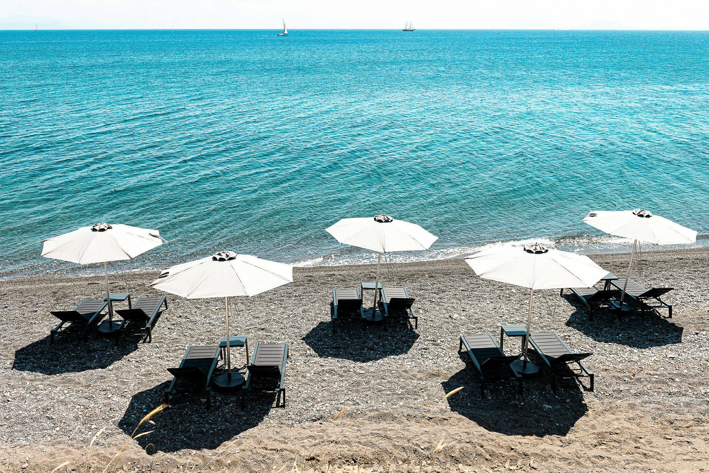 Strand med solsängar under vita parasoller vid havet. (AI-genererad text)