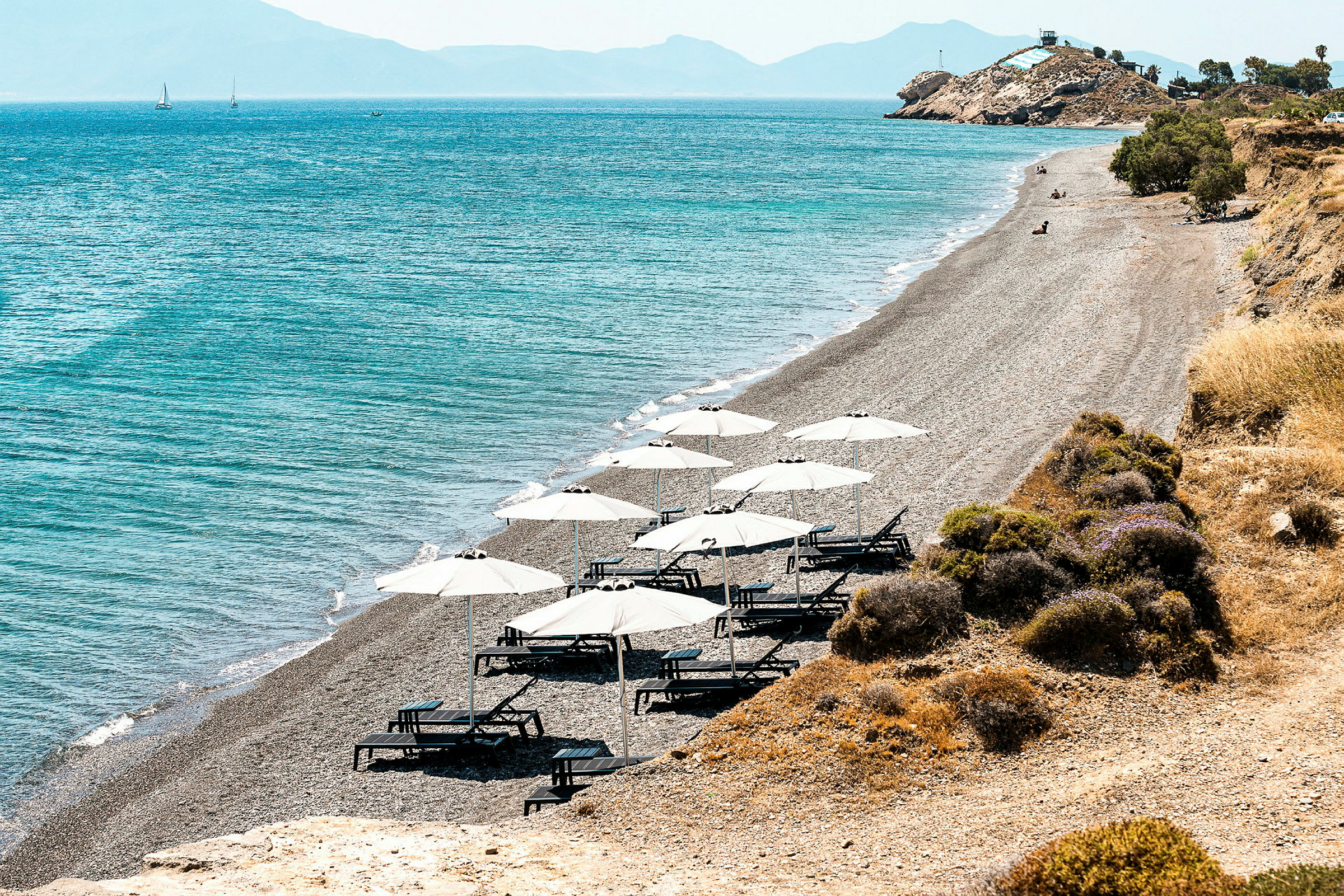 Strand med solstolar och parasoller vid havet. (AI-genererad text)