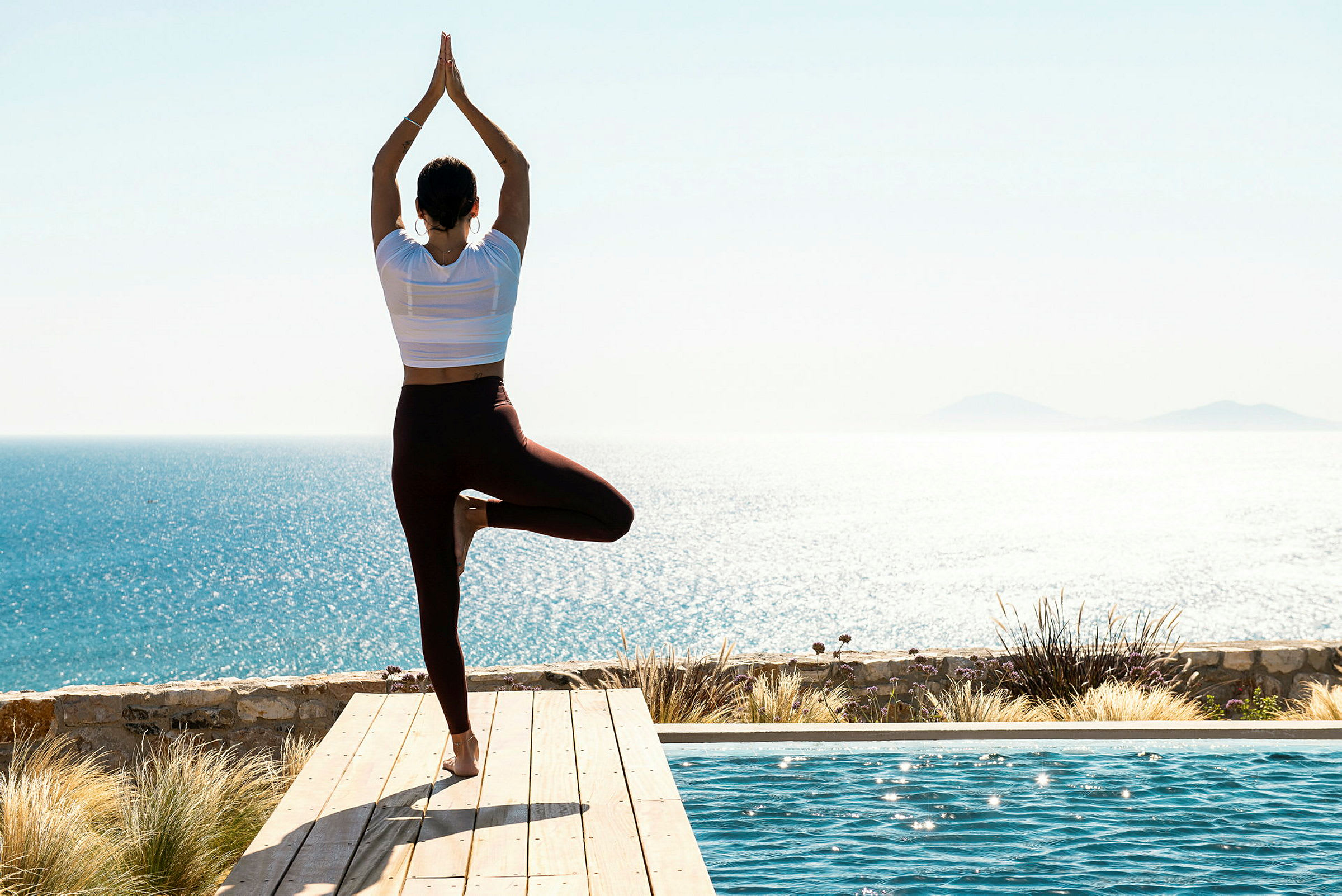 Person som gör yoga vid en pool med havsutsikt. (AI-genererad text)