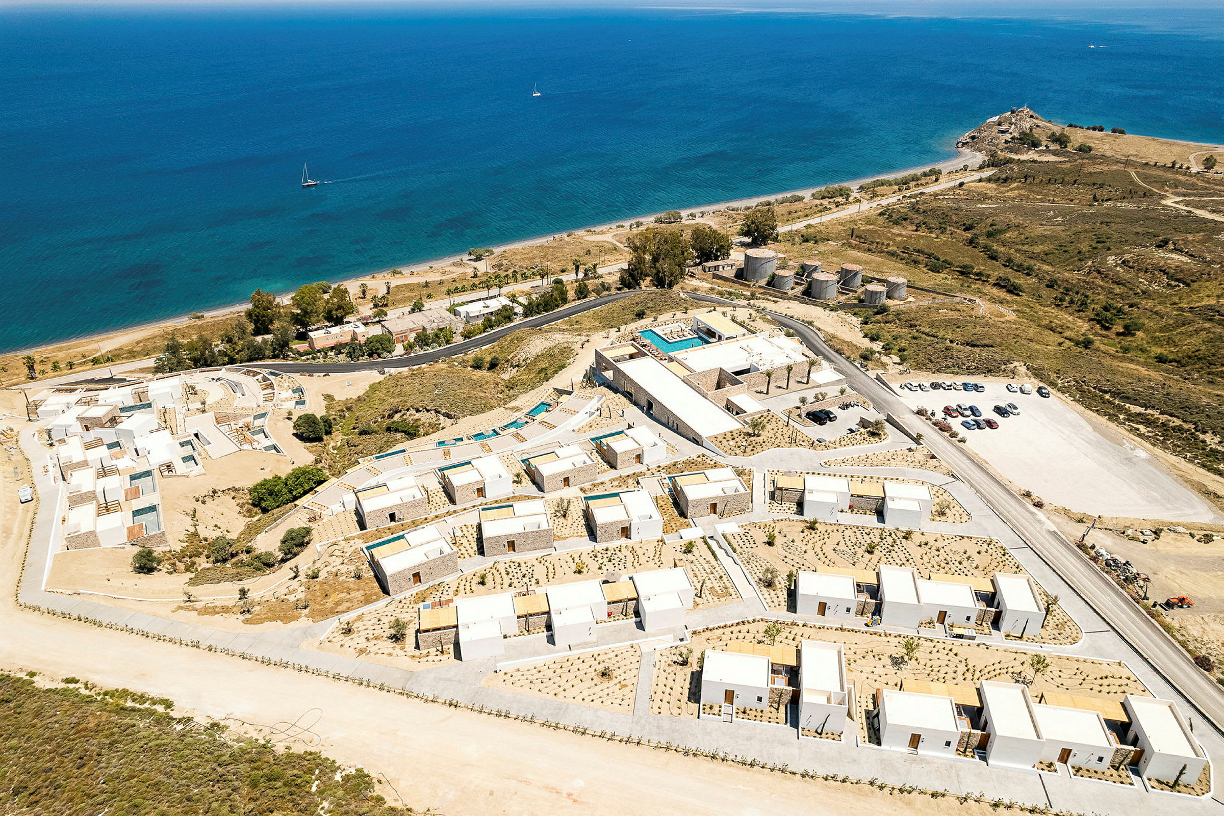 Bild av en resort vid havet med vita byggnader, en pool och parkeringsplats. (AI-genererad text)