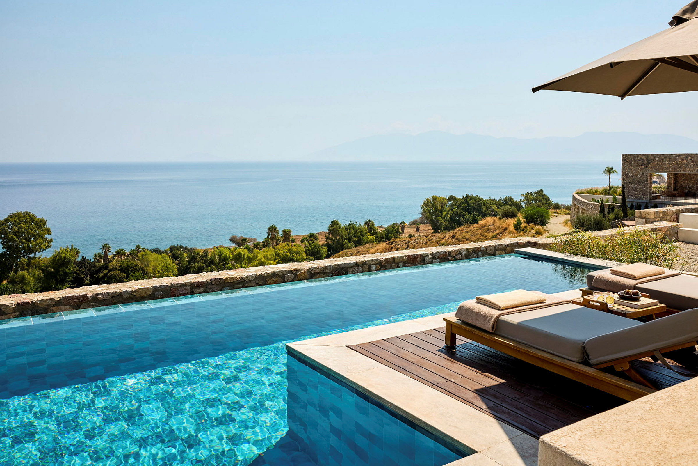 En infinitypool med utsikt över havet och ett grönskande landskap. (AI-genererad text)