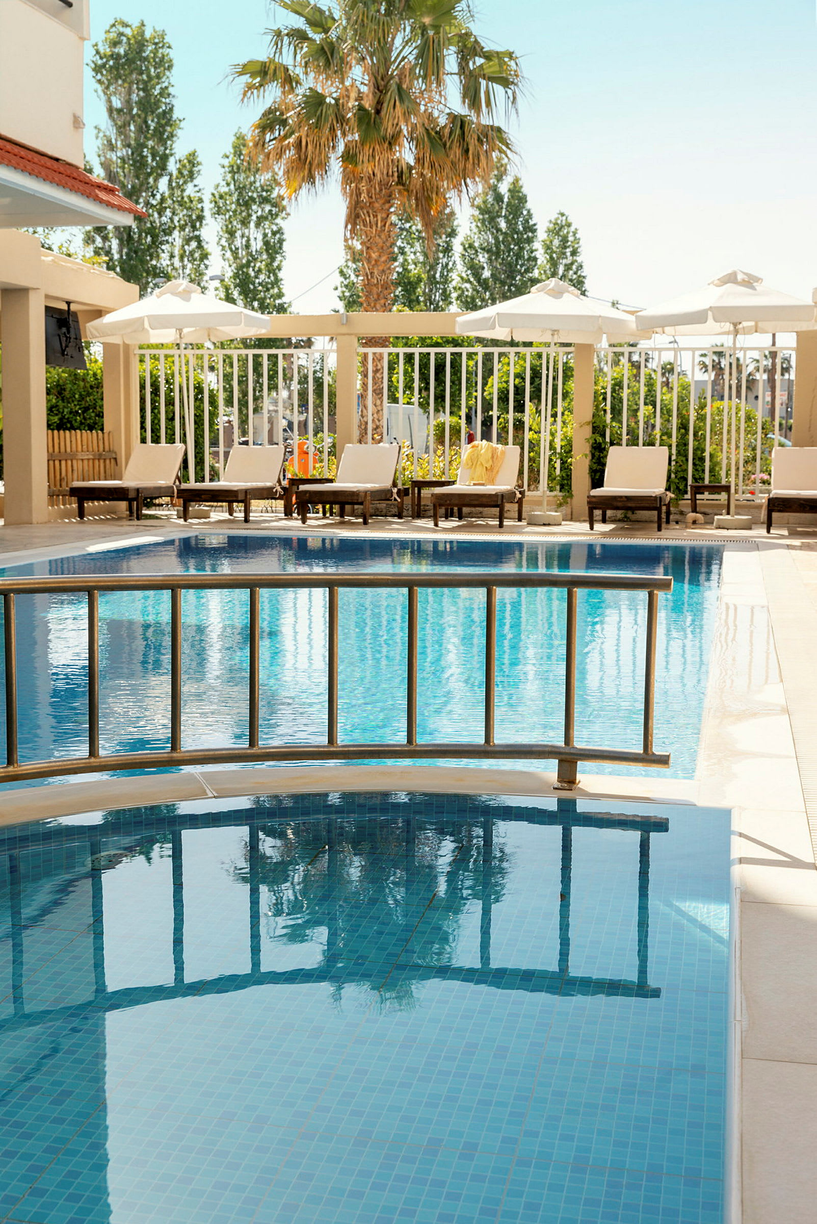 Hotellpool med solstolar och en palm i bakgrunden. (AI-genererad text)