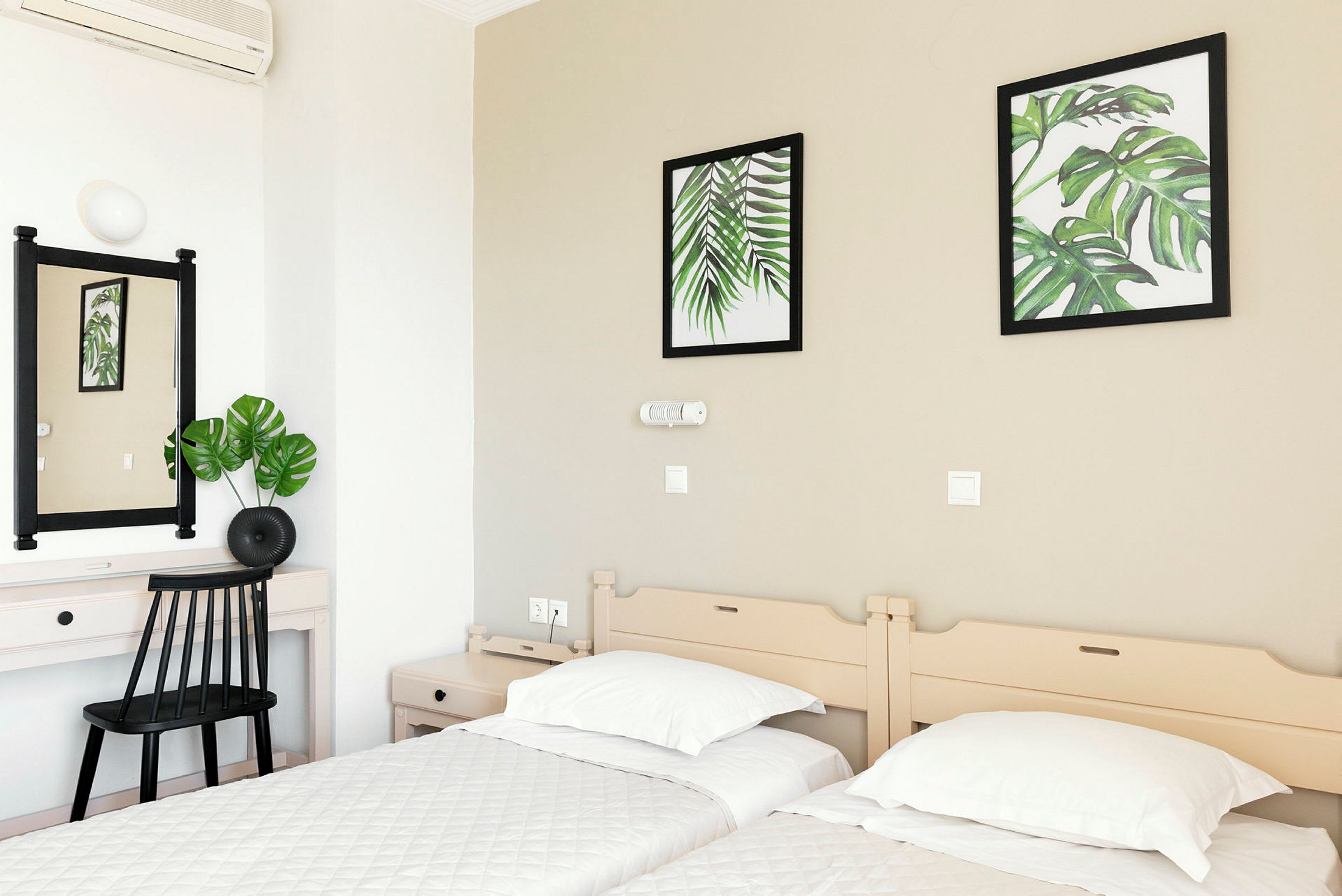 Hotellrum med två enkelsängar, ett skrivbord och väggdekorationer med botaniska motiv. (AI-genererad text)