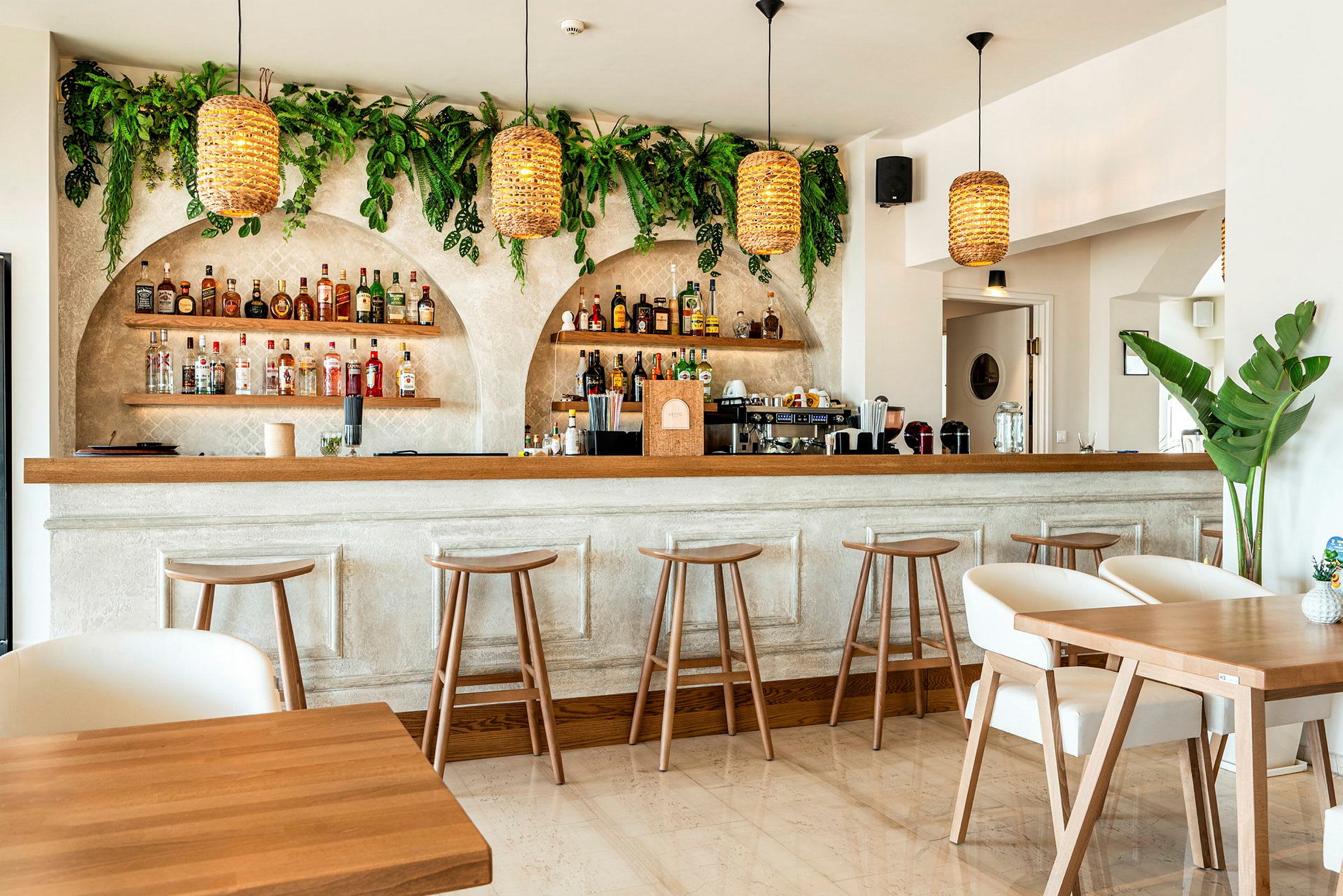 En inomhusbild av en modern bar med trästolar, bord och gröna växter på väggarna. (AI-genererad text)