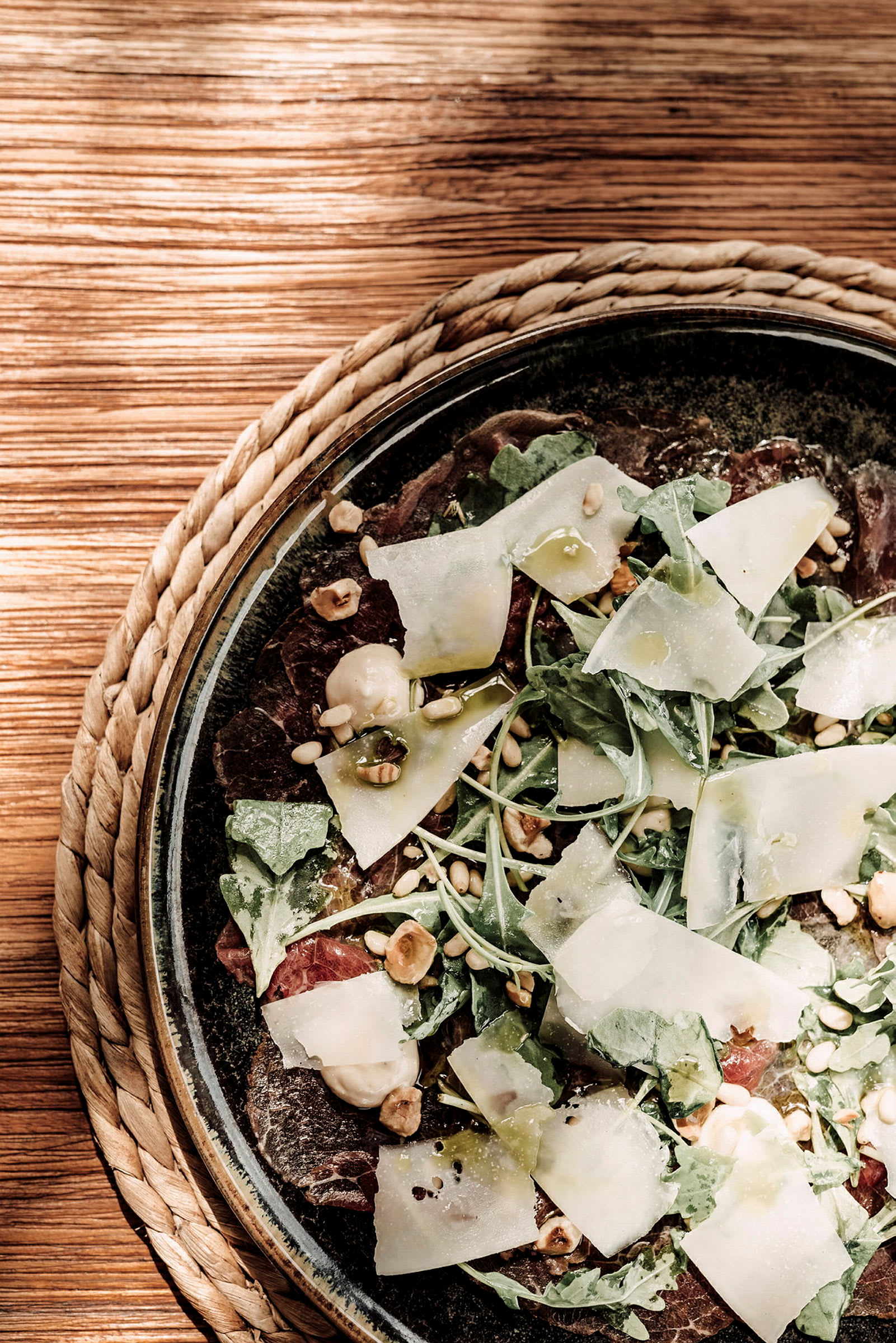 Närbild på en sallad med ruccola, tunna ostskivor, nötter och balsamicodressing. (AI-genererad text)