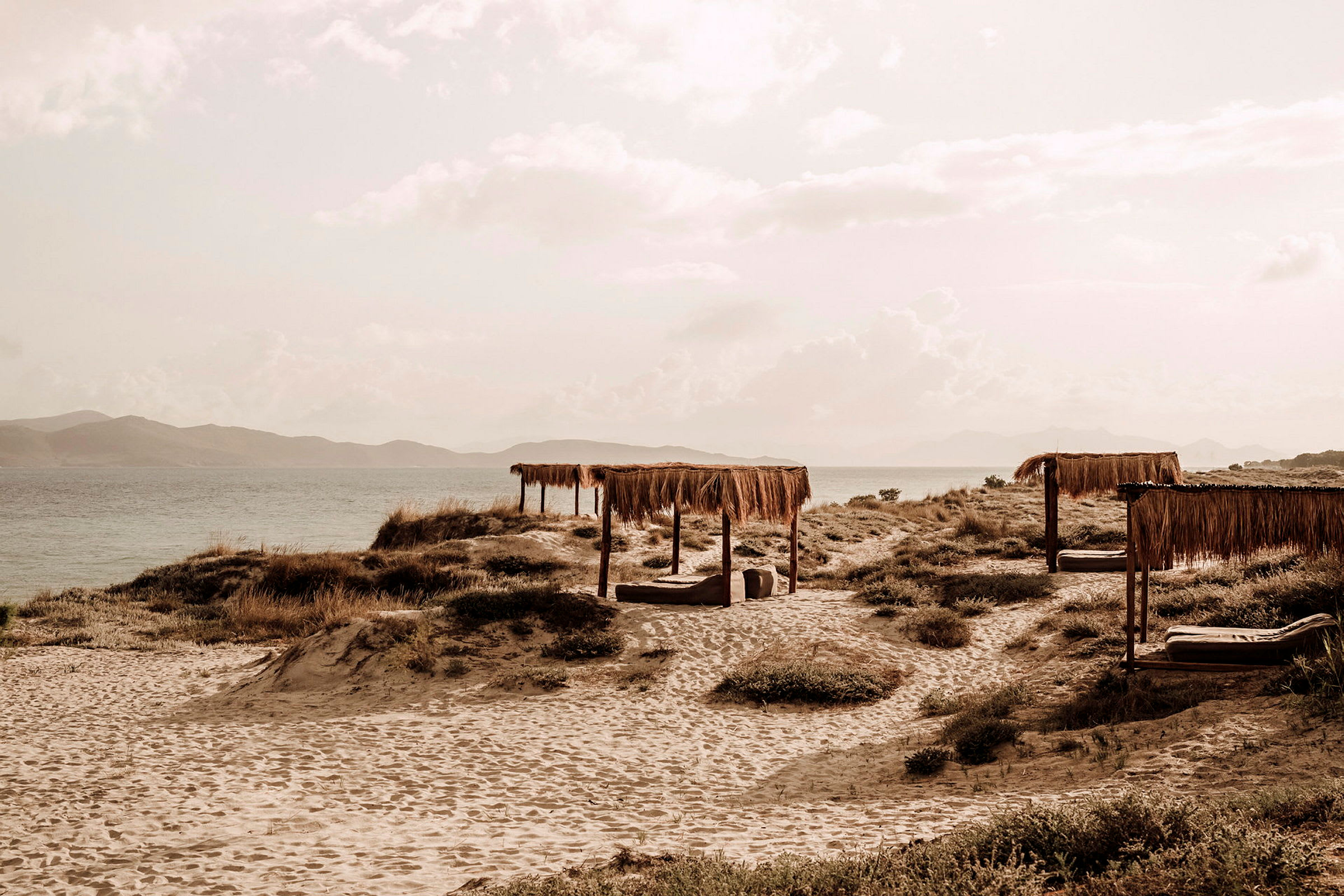 Strand med parasoller av vass med hav i bakgrunden. (AI-genererad text)