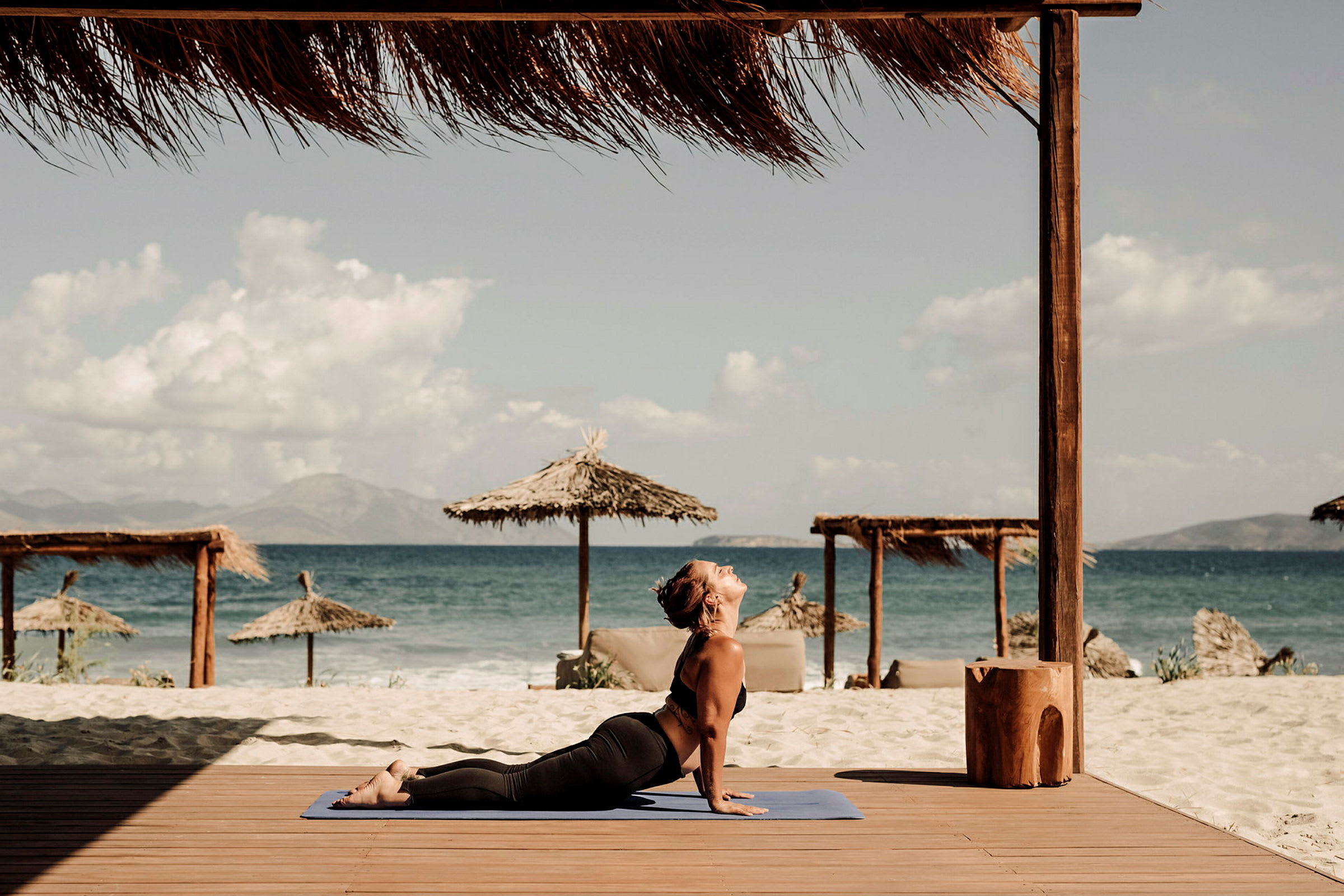 Person på en träplattform vid stranden och havet, utför yoga. (AI-genererad text)