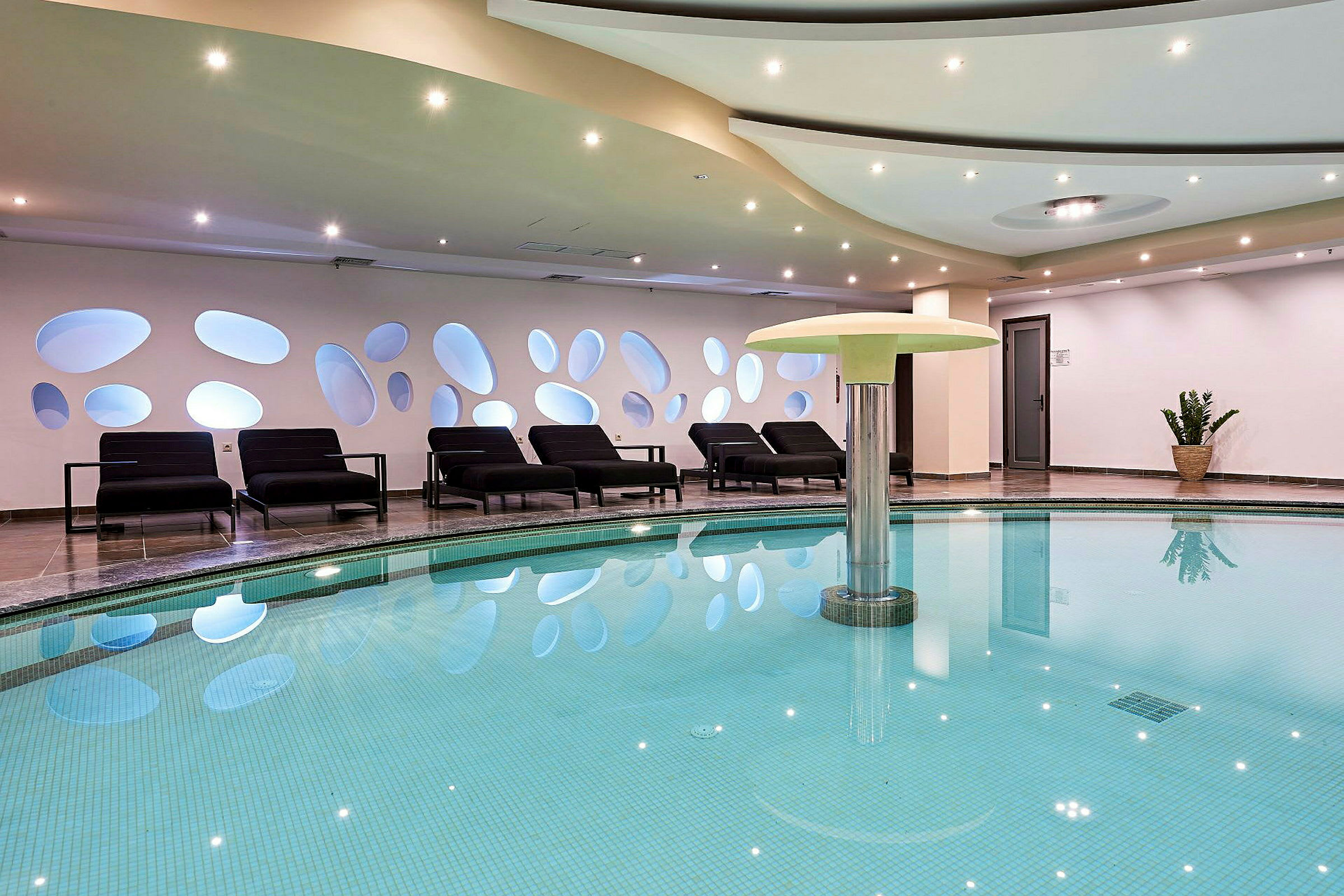 Interiör av ett spa med en swimmingpool och solstolar. (AI-genererad text)
