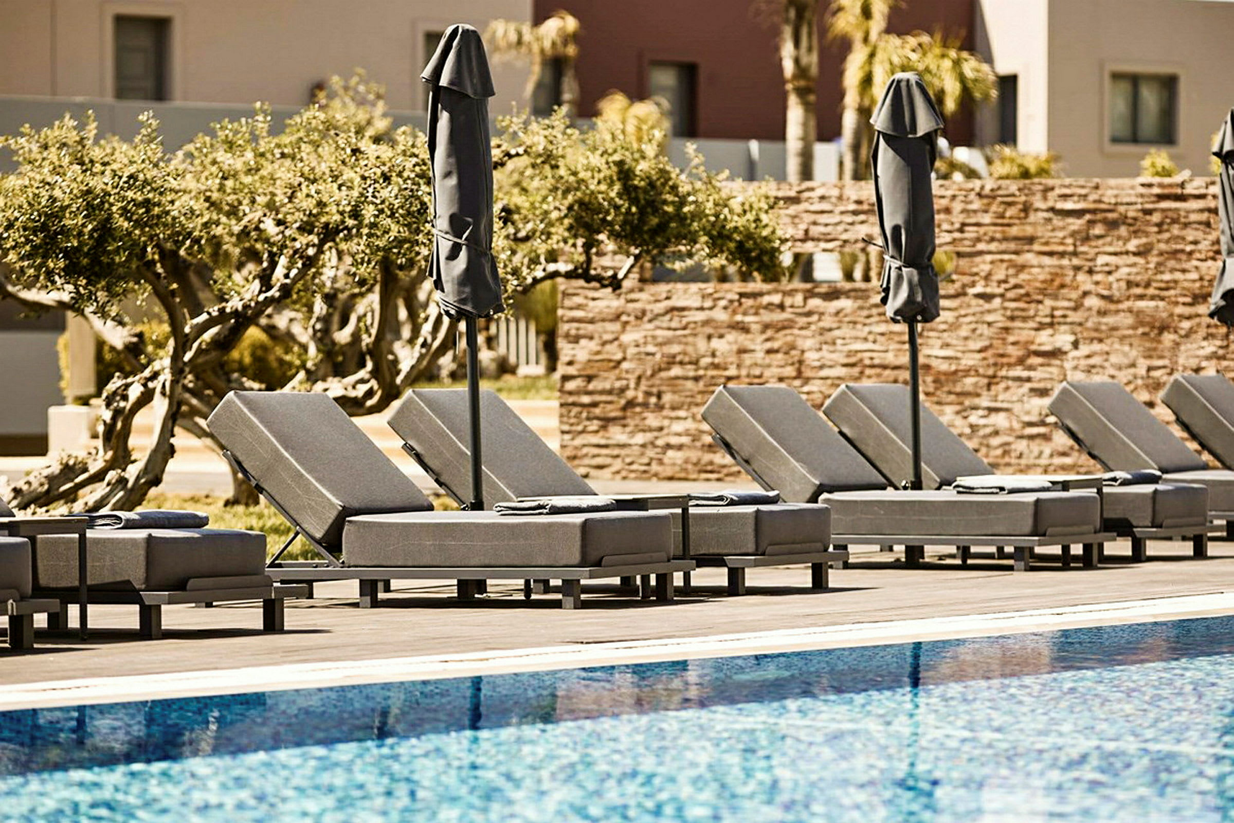 Solstolar med parasoller vid en pool. (AI-genererad text)