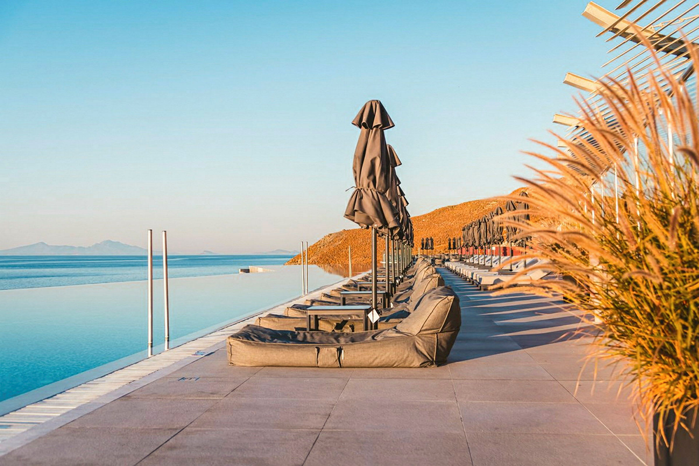 Solstolar och parasoller vid en infinitypool med havsutsikt. (AI-genererad text)