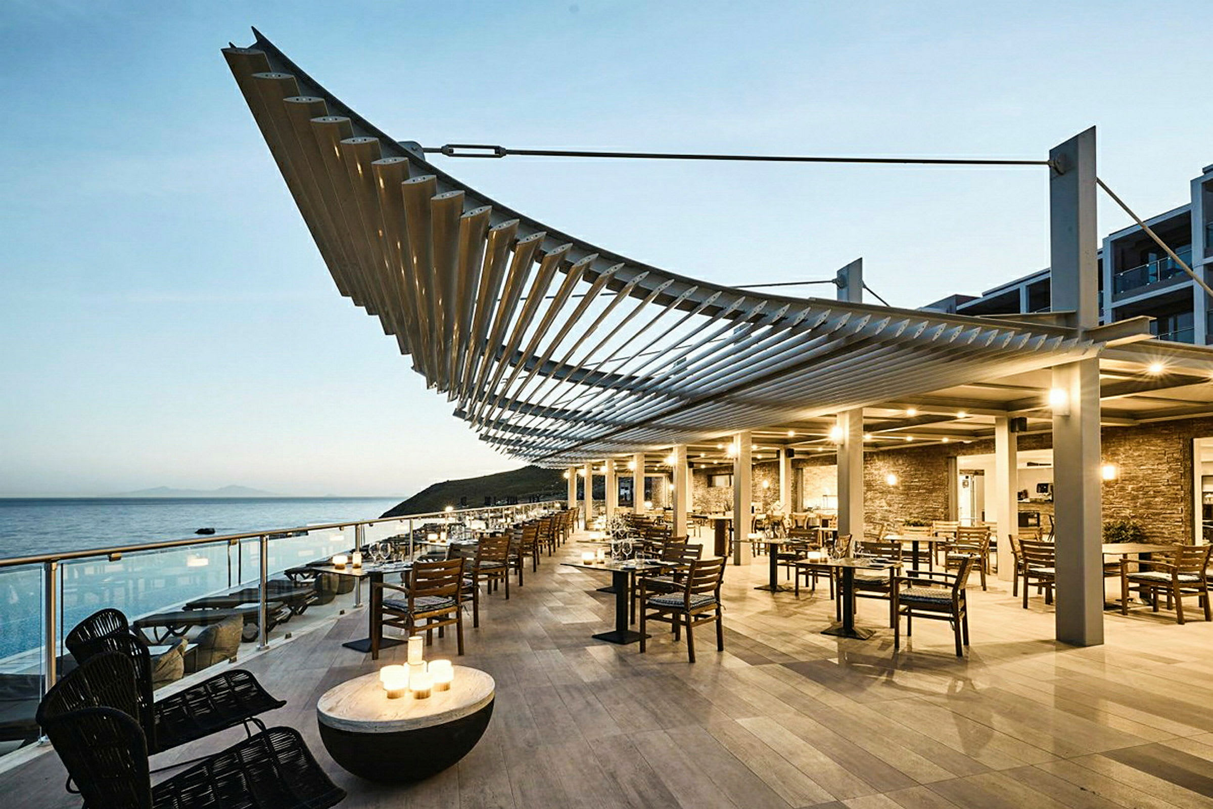 Restaurang med sittplatser utomhus vid havet under en modern pergola. (AI-genererad text)