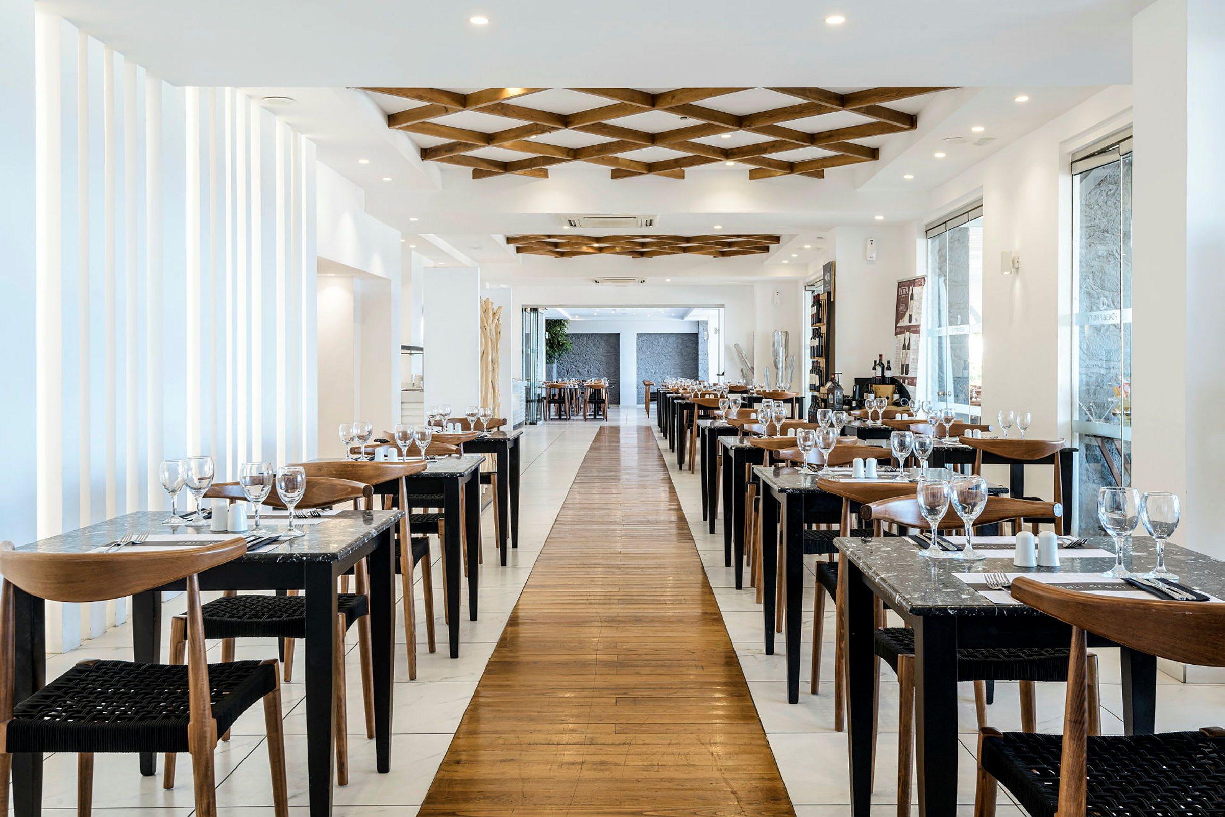 En elegant restaurang med uppställda bord och stolar längs båda sidor av en gång, dekorerad med modern inredning. (AI-genererad text)