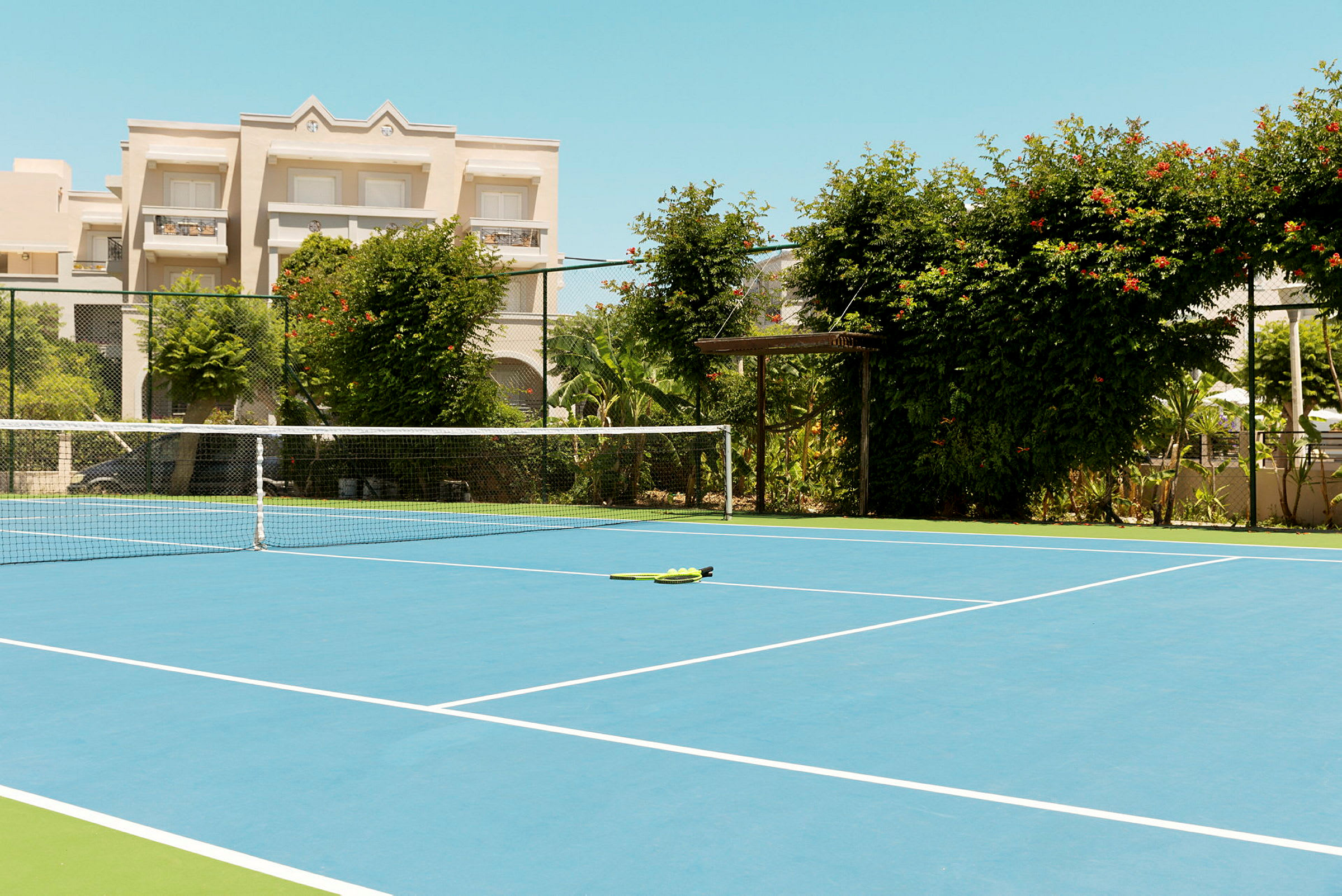 En tennisbana med ett nät och grön växtlighet runt om. (AI-genererad text)