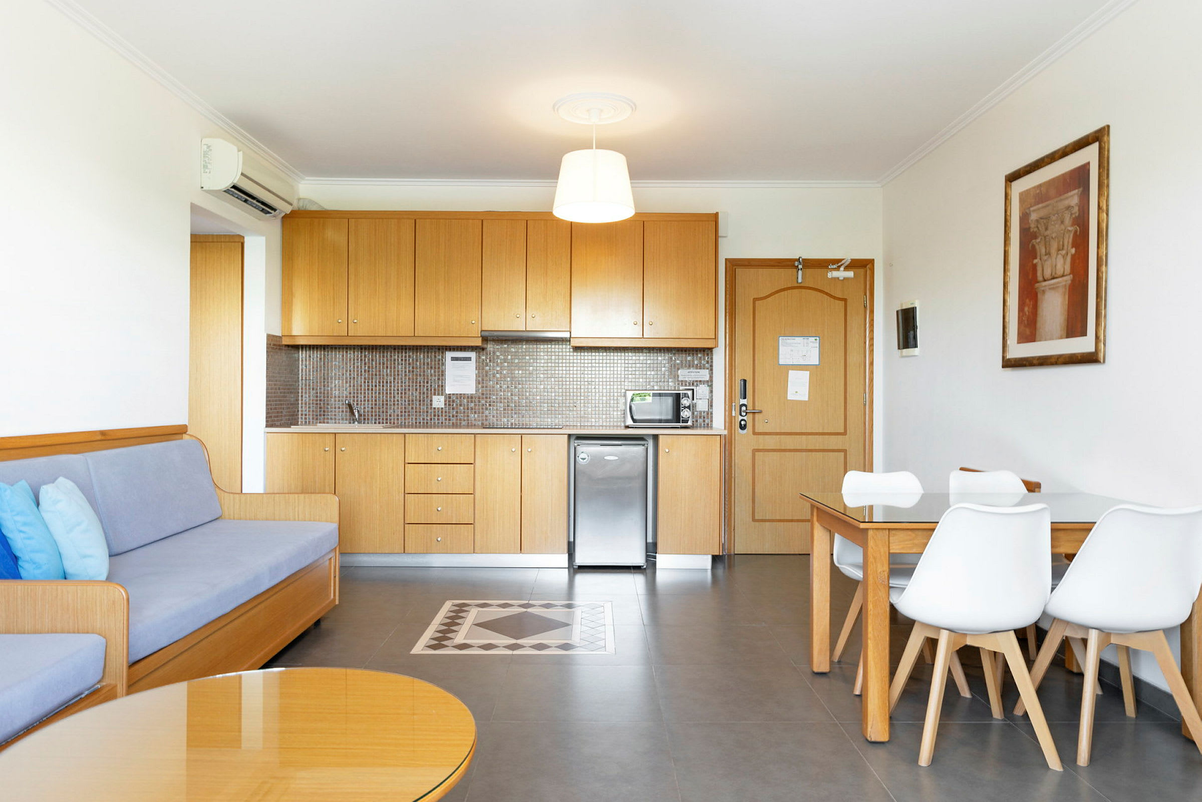 Ett hotellrum med köksdel, matbord och soffa. (AI-genererad text)