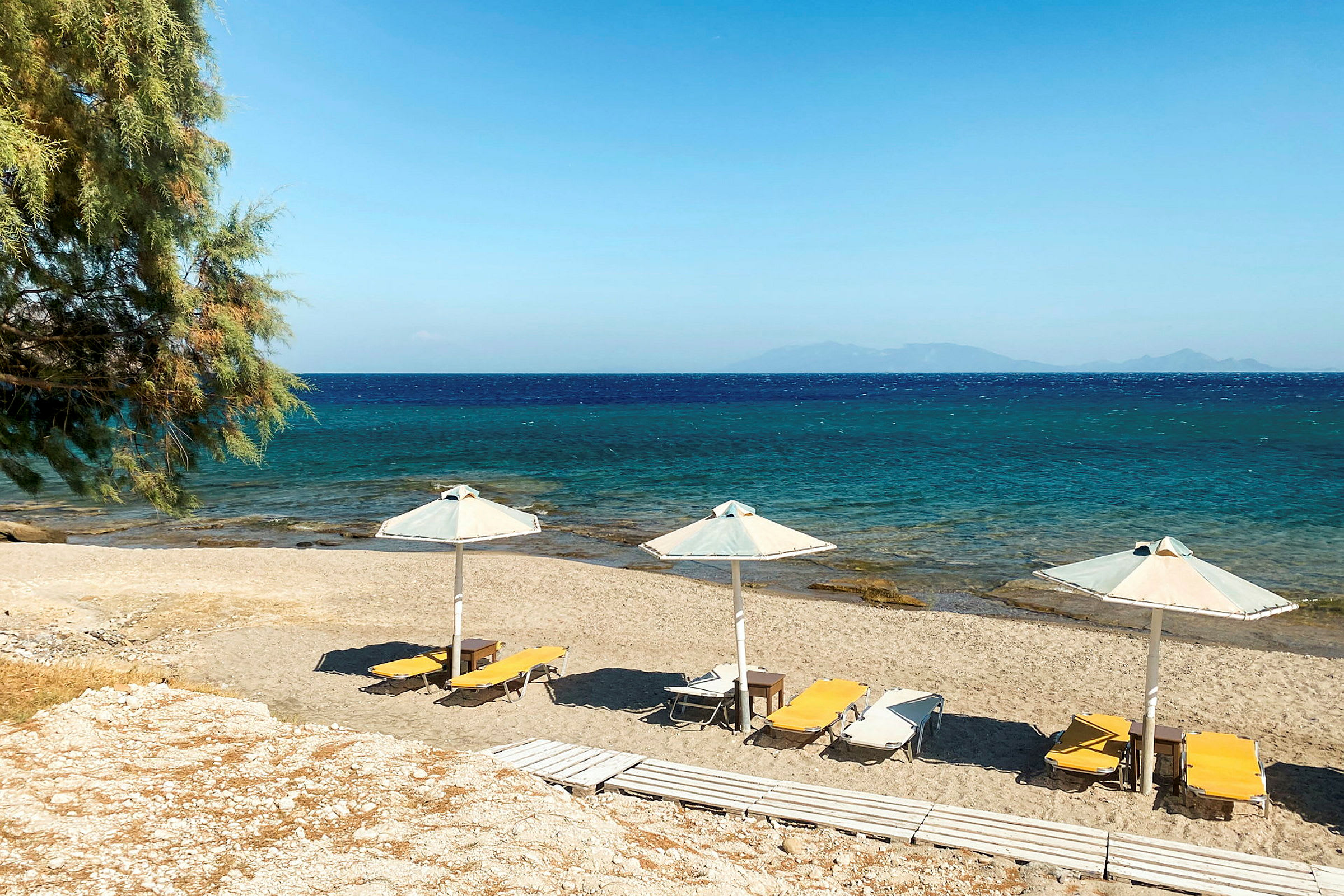 Sandstrand med solstolar och parasoller vid havet. (AI-genererad text)
