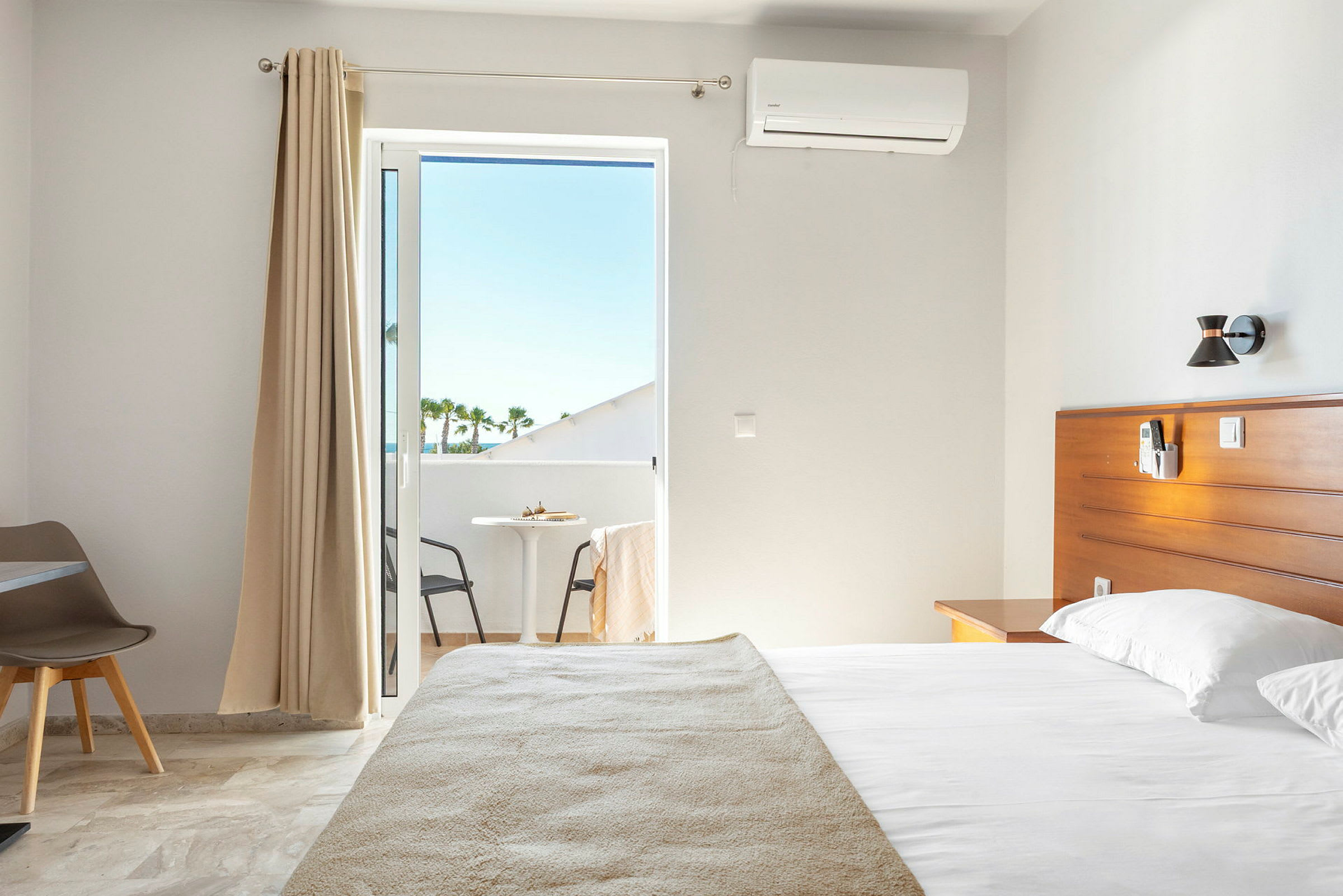 Inuti ett hotellrum med säng och balkong. (AI-genererad text)