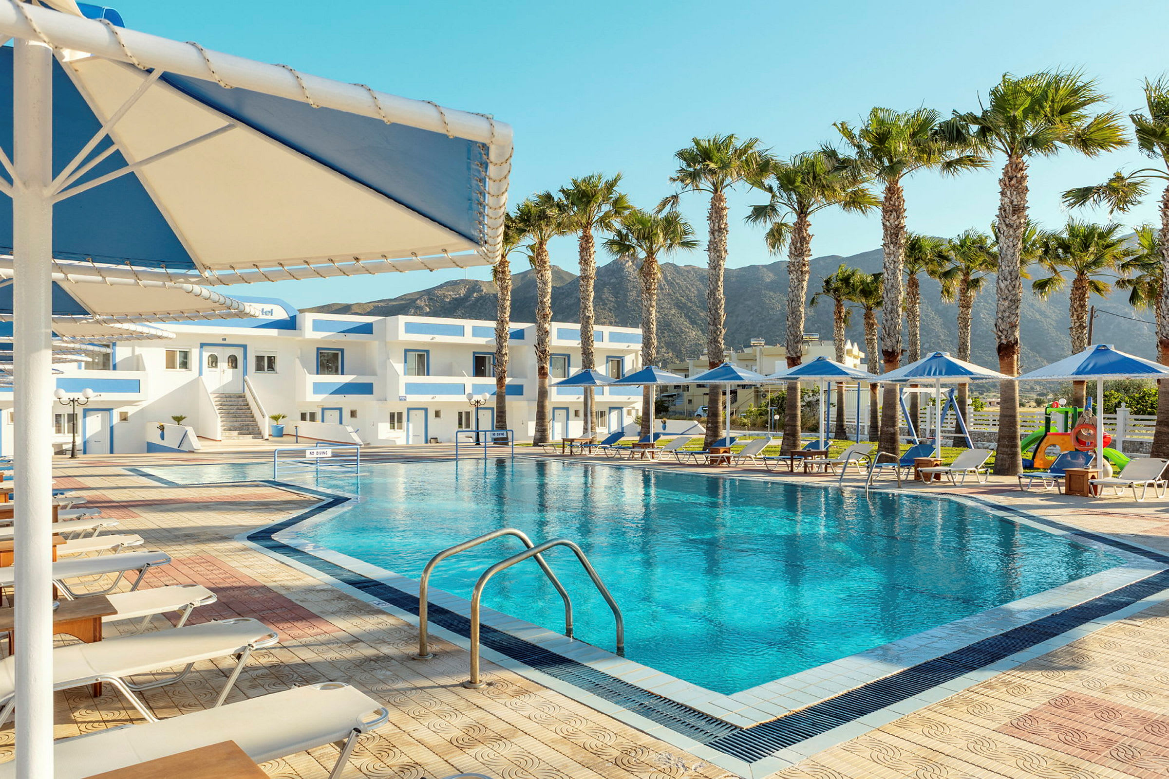En pool med solstolar omkring och byggnader i bakgrunden. (AI-genererad text)