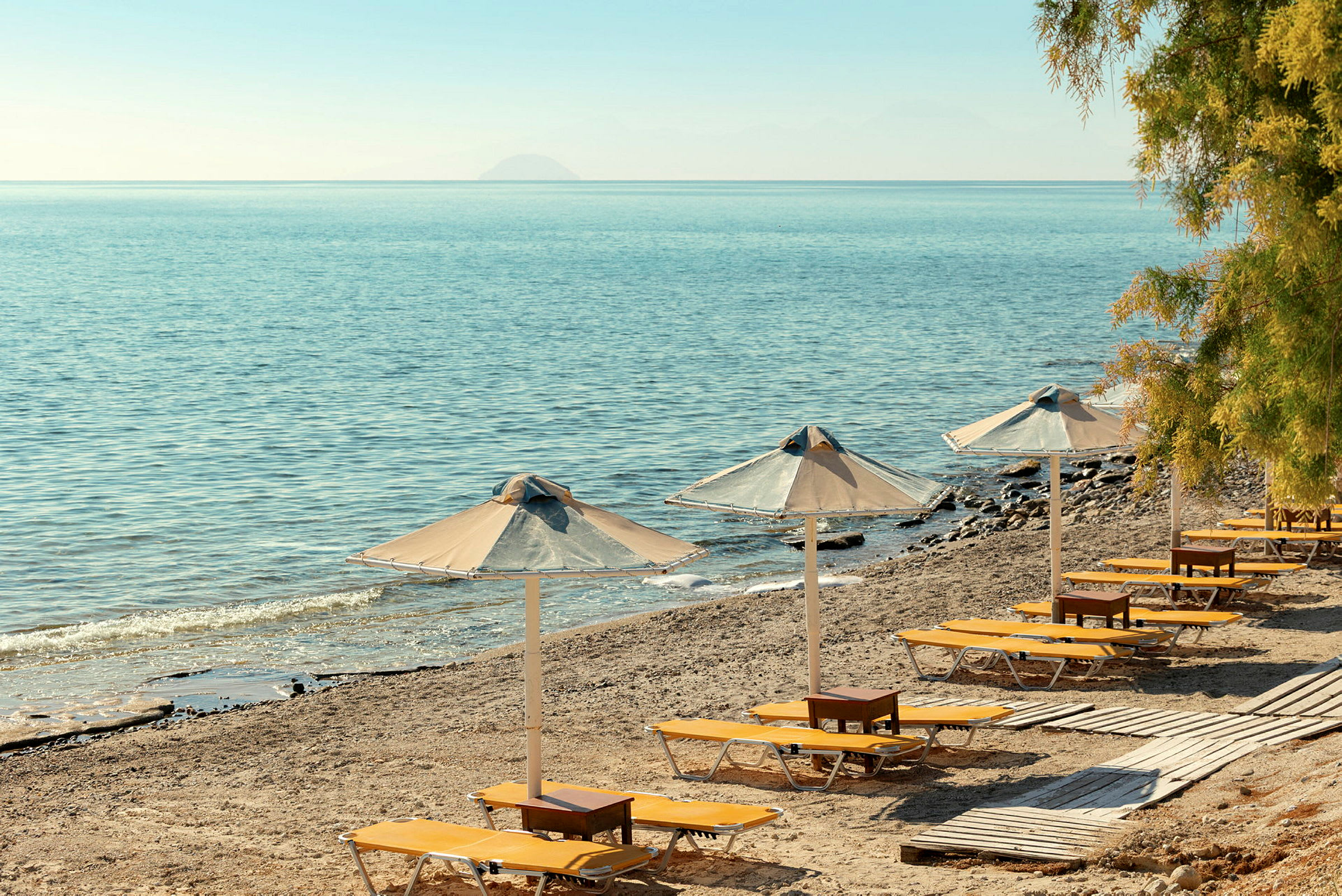 Solstolar och parasoller på en sandstrand med utsikt över havet. (AI-genererad text)