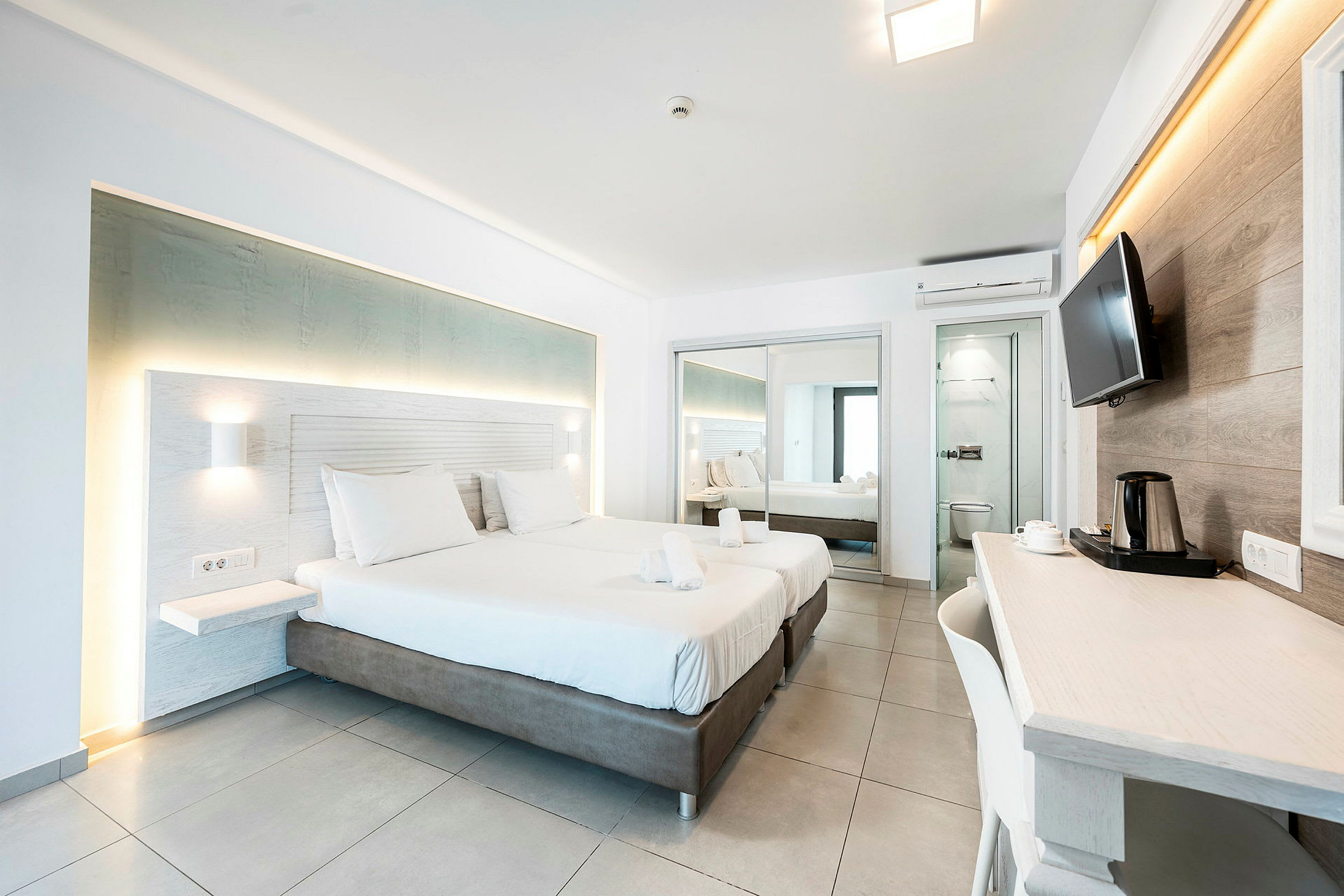 Modernt hotellrum med två bäddar, skrivbord och speglar. (AI-genererad text)
