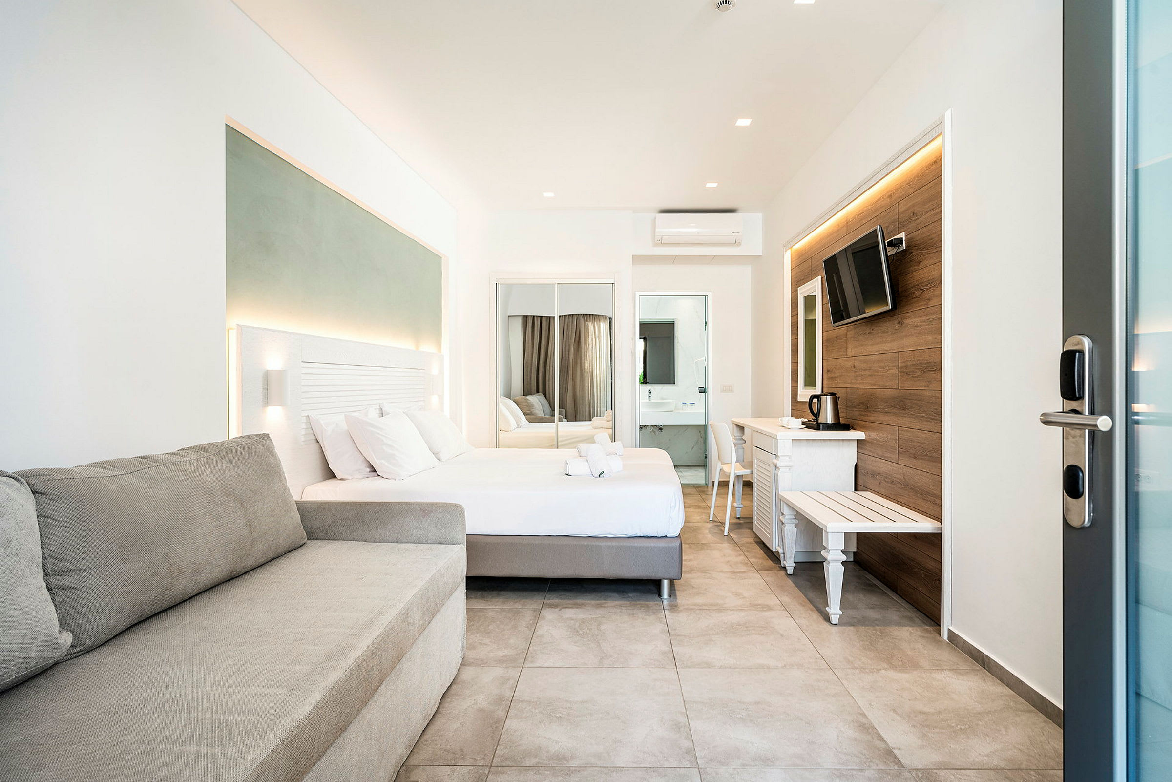 Modernt hotellrum med säng, soffa och TV. (AI-genererad text)