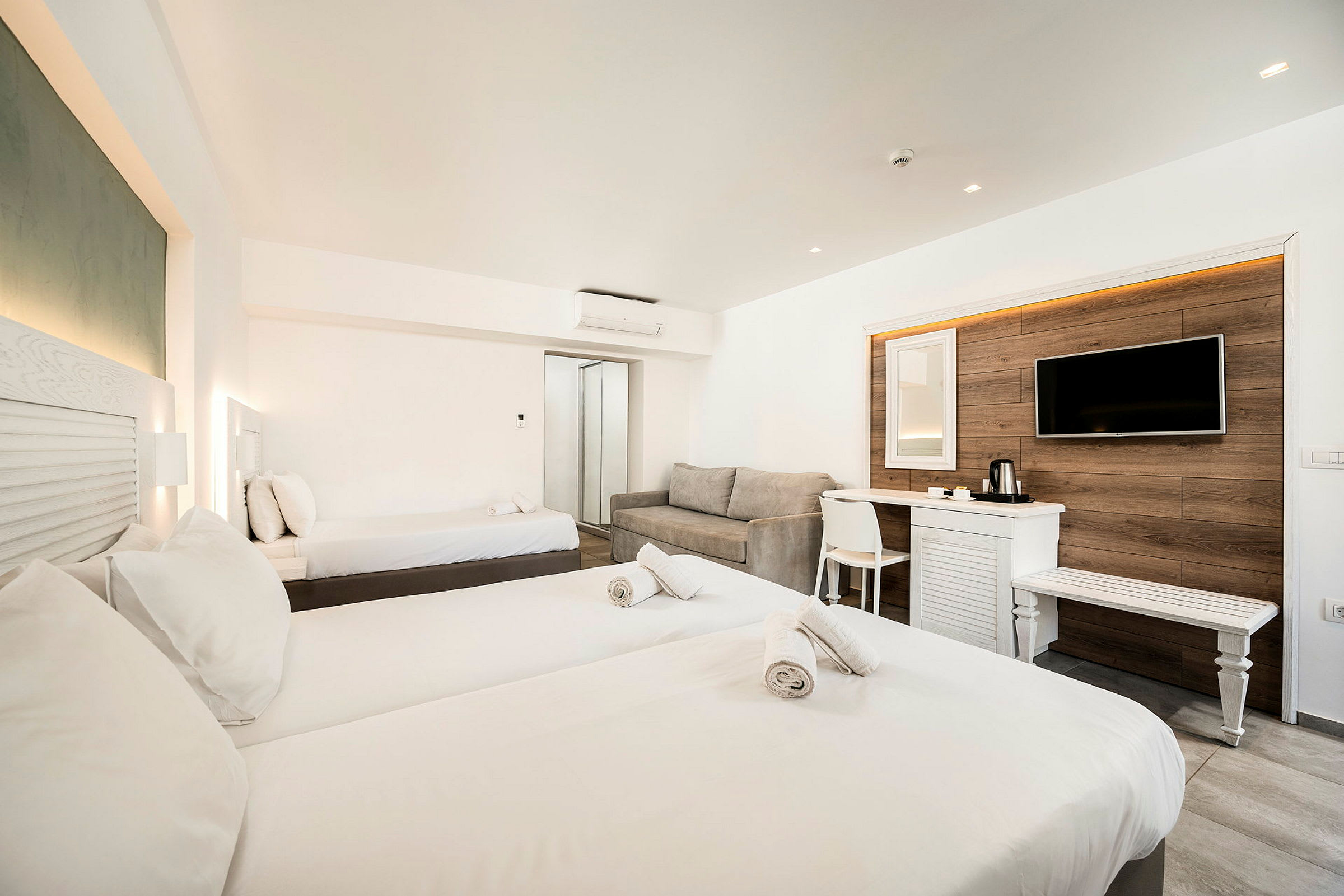 Inredningen i ett hotellrum med två sängar, en soffa och en väggmonterad TV. (AI-genererad text)