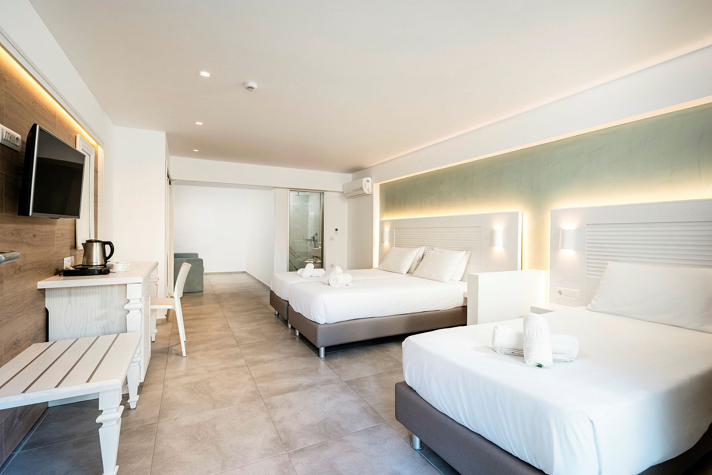 Modernt hotellrum med två dubbelsängar, möbler och utsikt mot badrummet. (AI-genererad text)