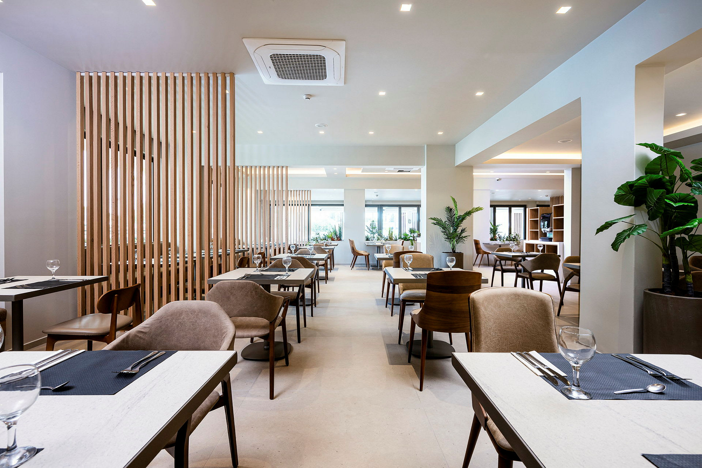 En modern restaurang med bord och stolar samt grönska. (AI-genererad text)