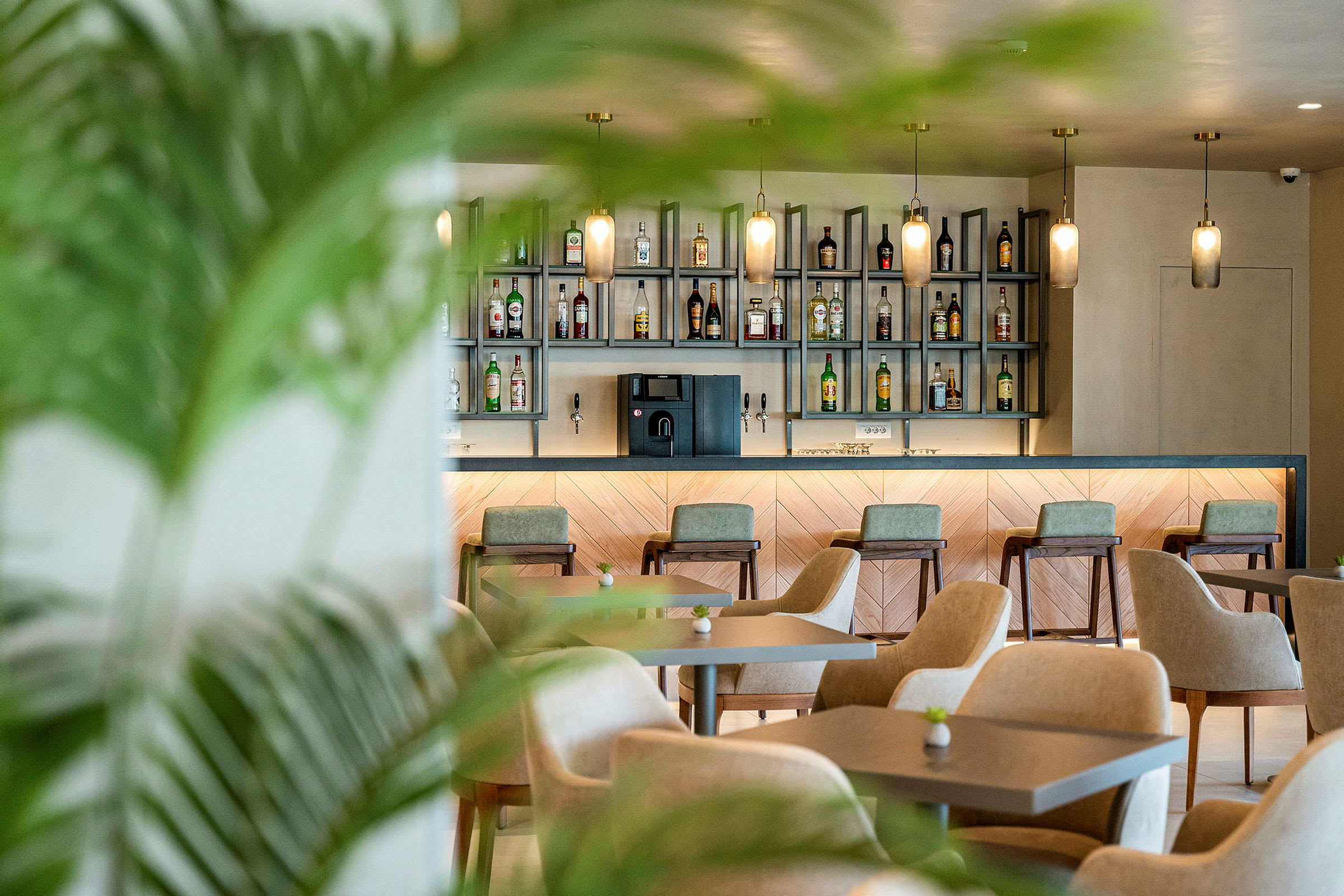 En modern bar med stolar och bord placerade framför en hylla fylld med flaskor. (AI-genererad text)