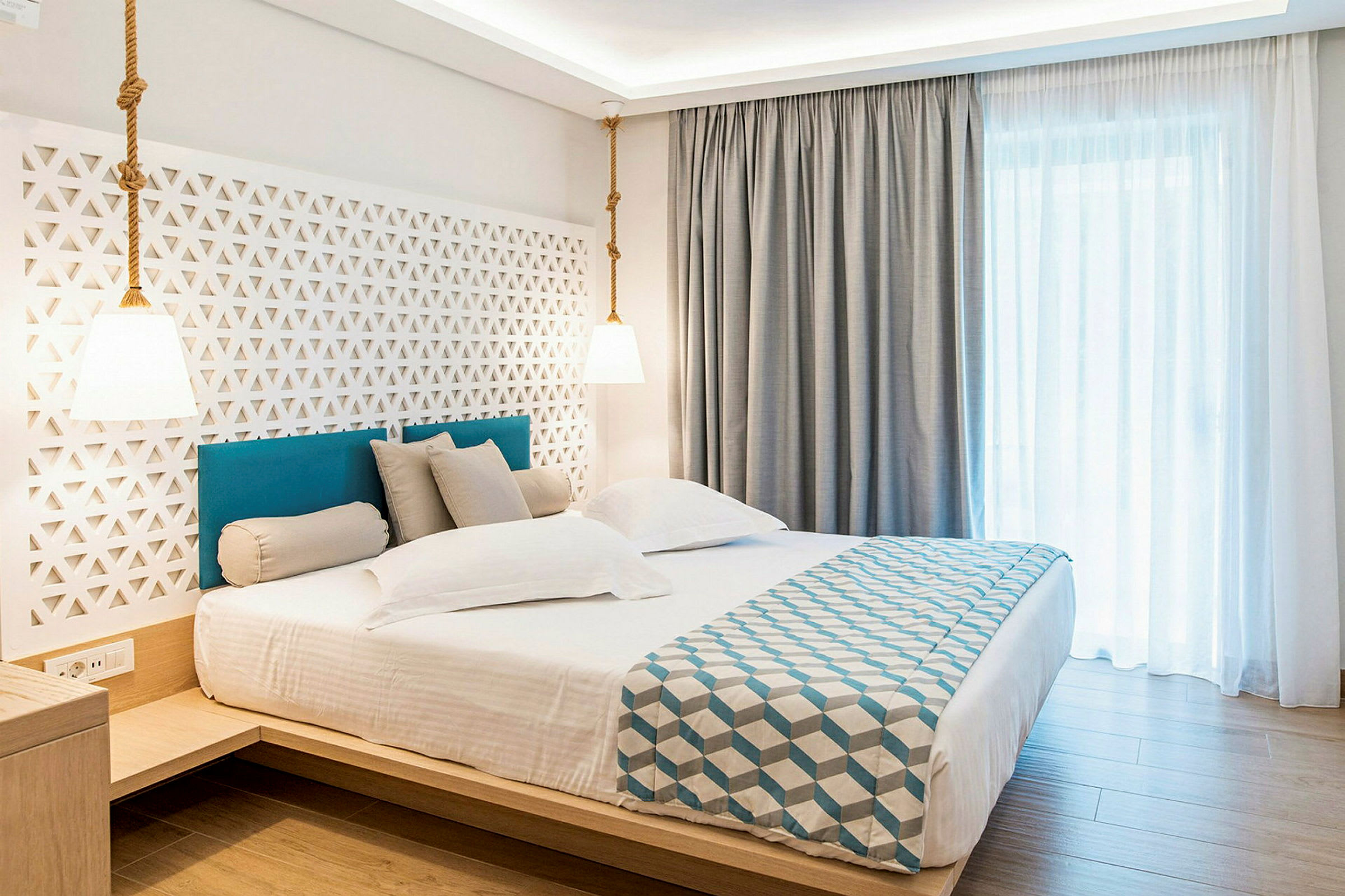 Hotellrum med en dubbel säng, stilren inredning och ljusa gardiner. (AI-genererad text)