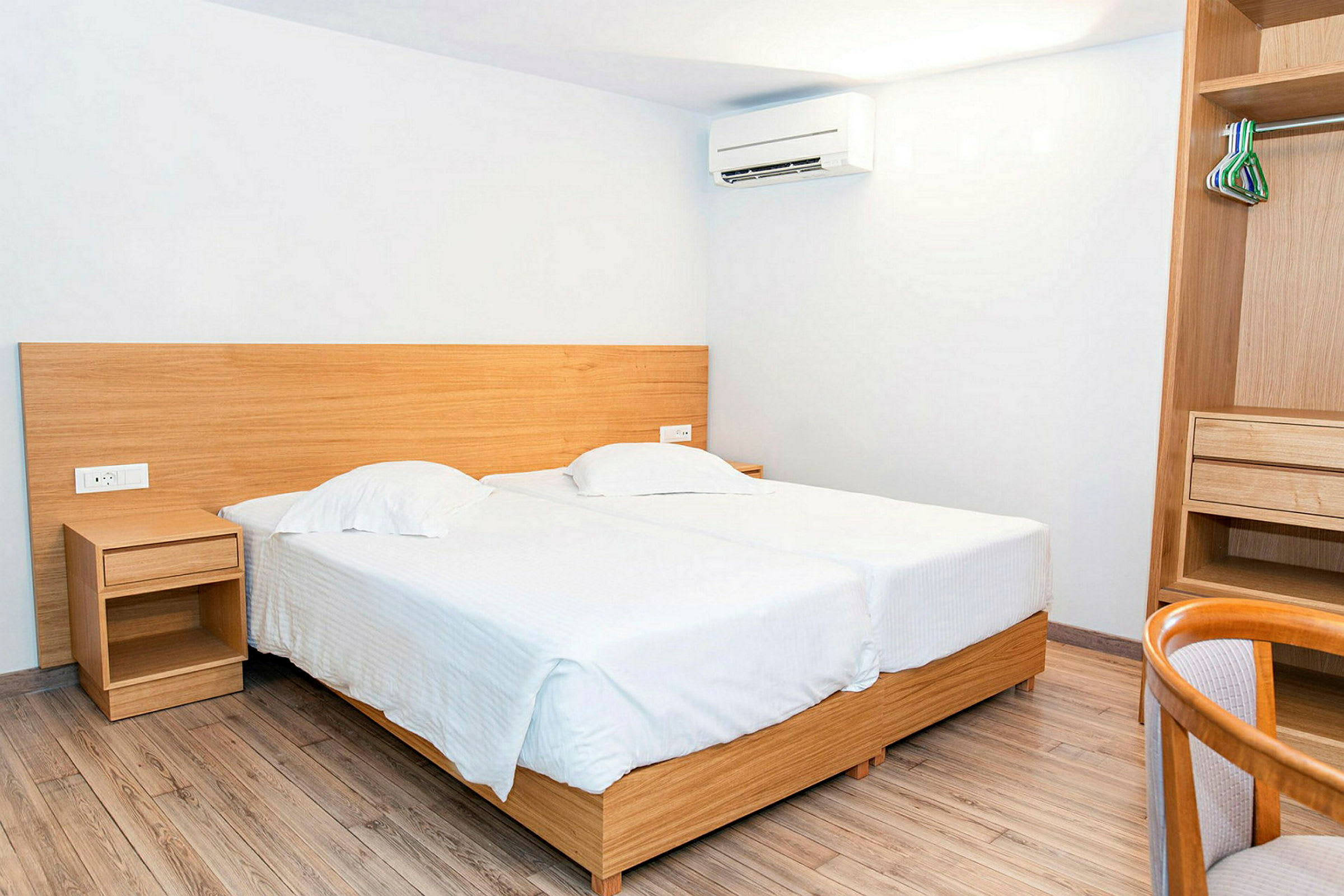 Inredning av ett hotellrum med två enkelsängar och en öppen garderob. (AI-genererad text)