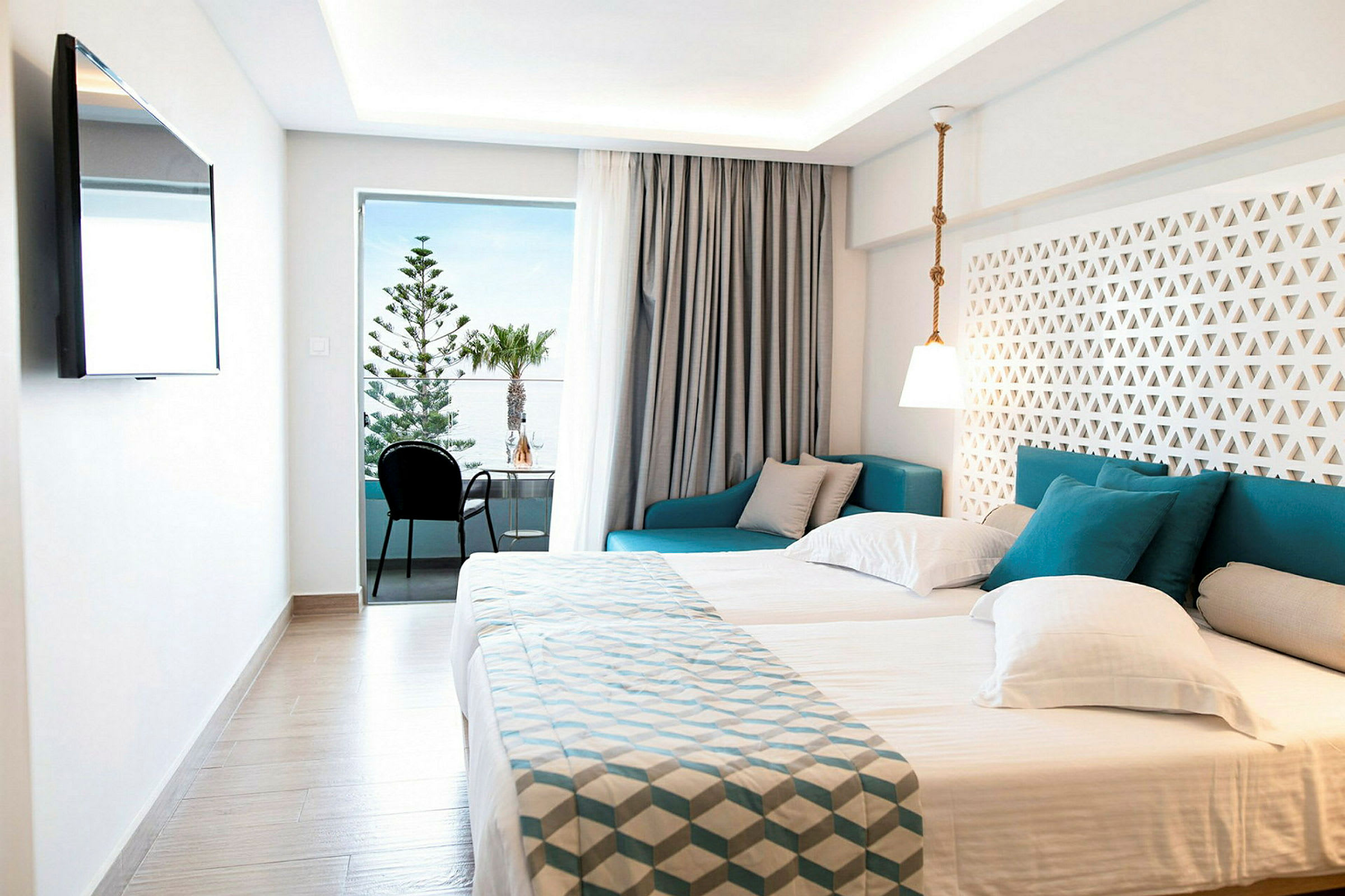 Modernt hotellrum med dubbelsäng, sittgrupp och balkong med utsikt. (AI-genererad text)