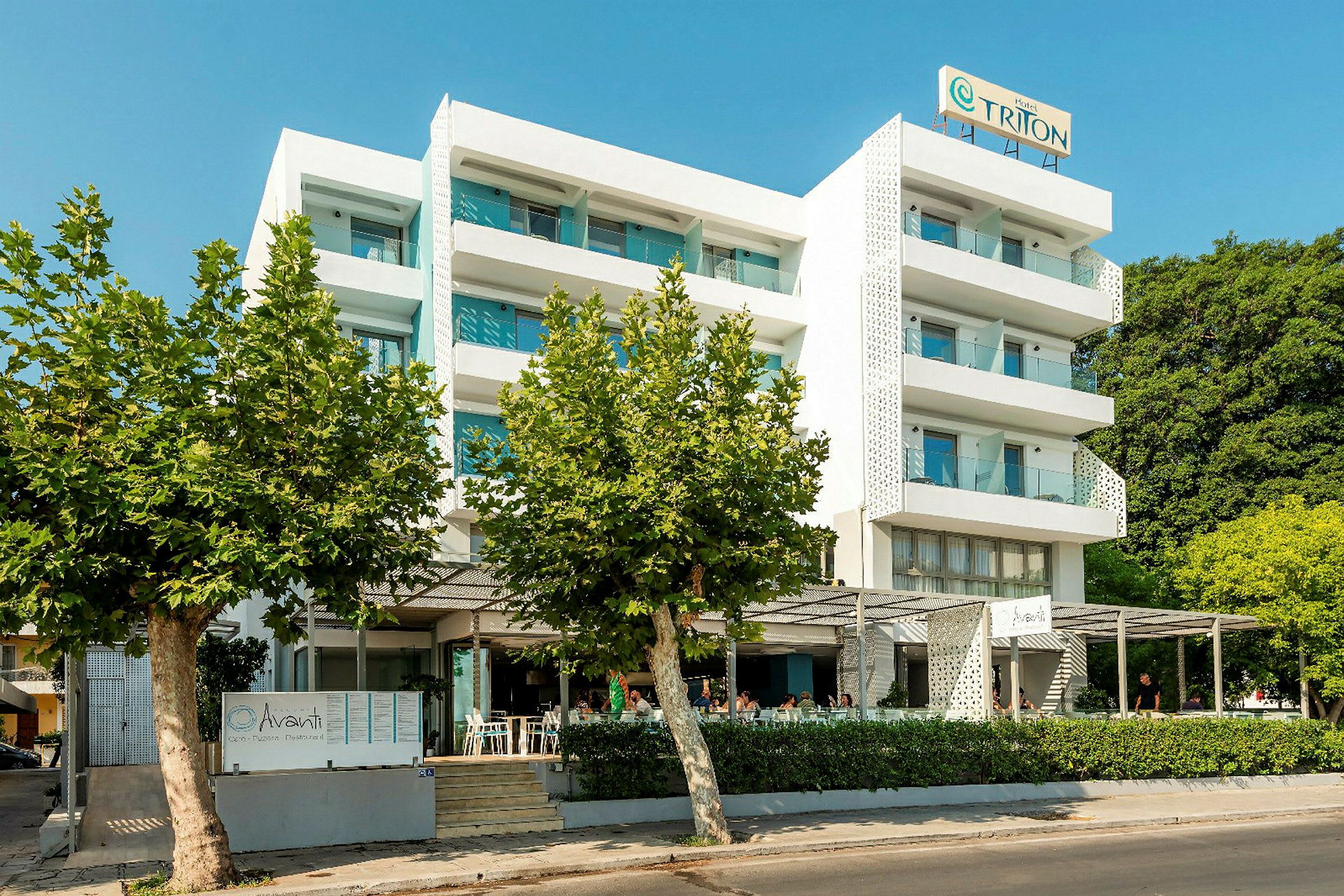 Fler våningshotell med vita fasader, balkonger och restaurang framför byggnaden. (AI-genererad text)