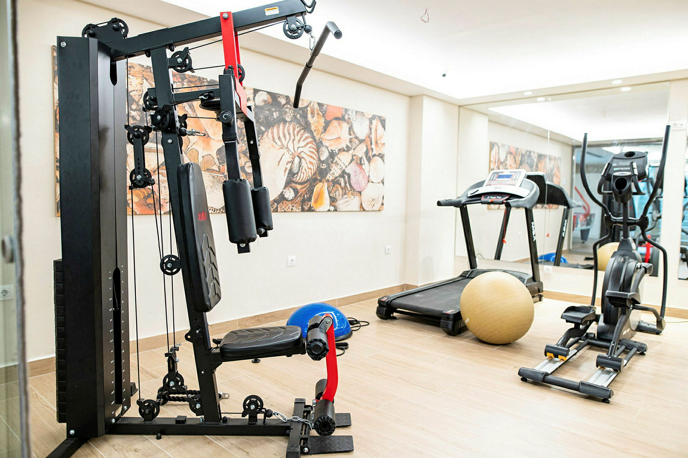 Bild på ett gym med träningsutrustning, inklusive en maskin med vikter, ett löpband och en motionscykel. (AI-genererad text)