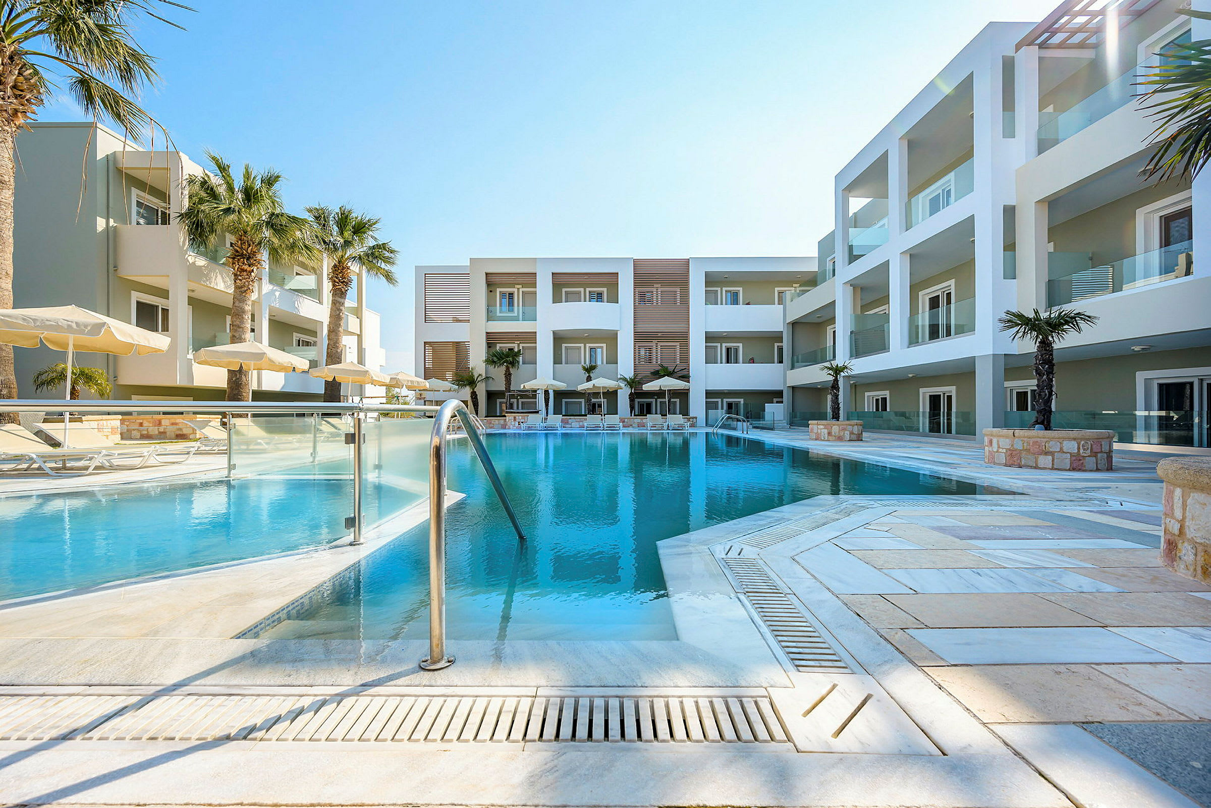 En pool framför ett modernt hotell med palmer och parasoller. (AI-genererad text)