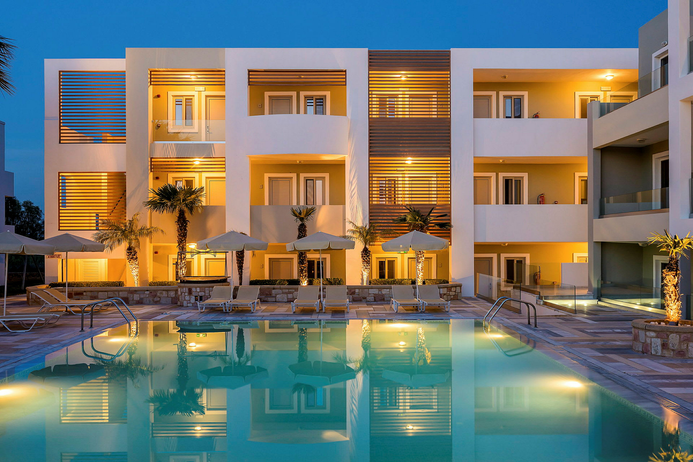 Bild av en modern hotellbyggnad med upplysta balkonger och en pool i förgrunden. (AI-genererad text)