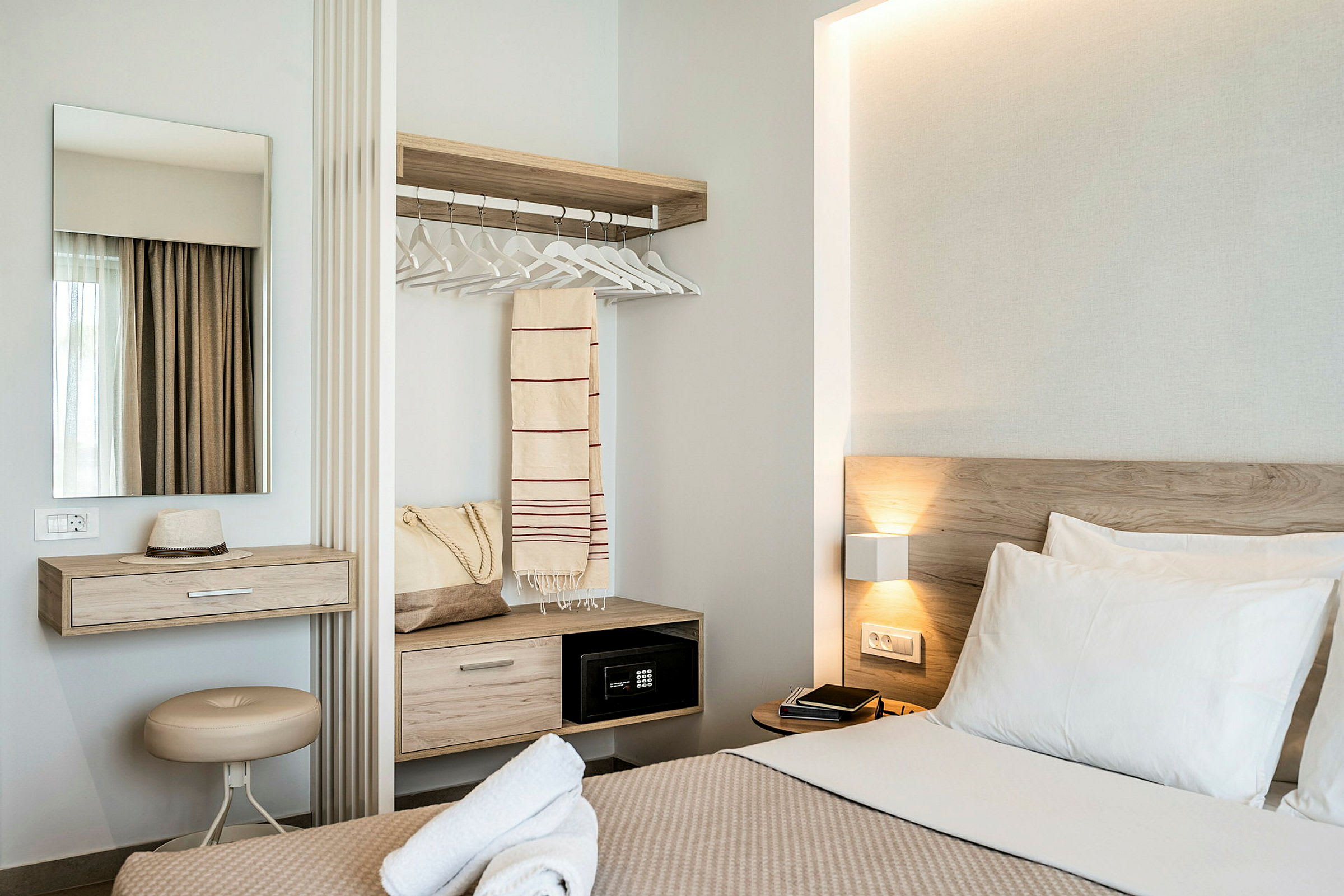 Modernt hotellrum med säng, skrivbord, spegel och garderob. (AI-genererad text)