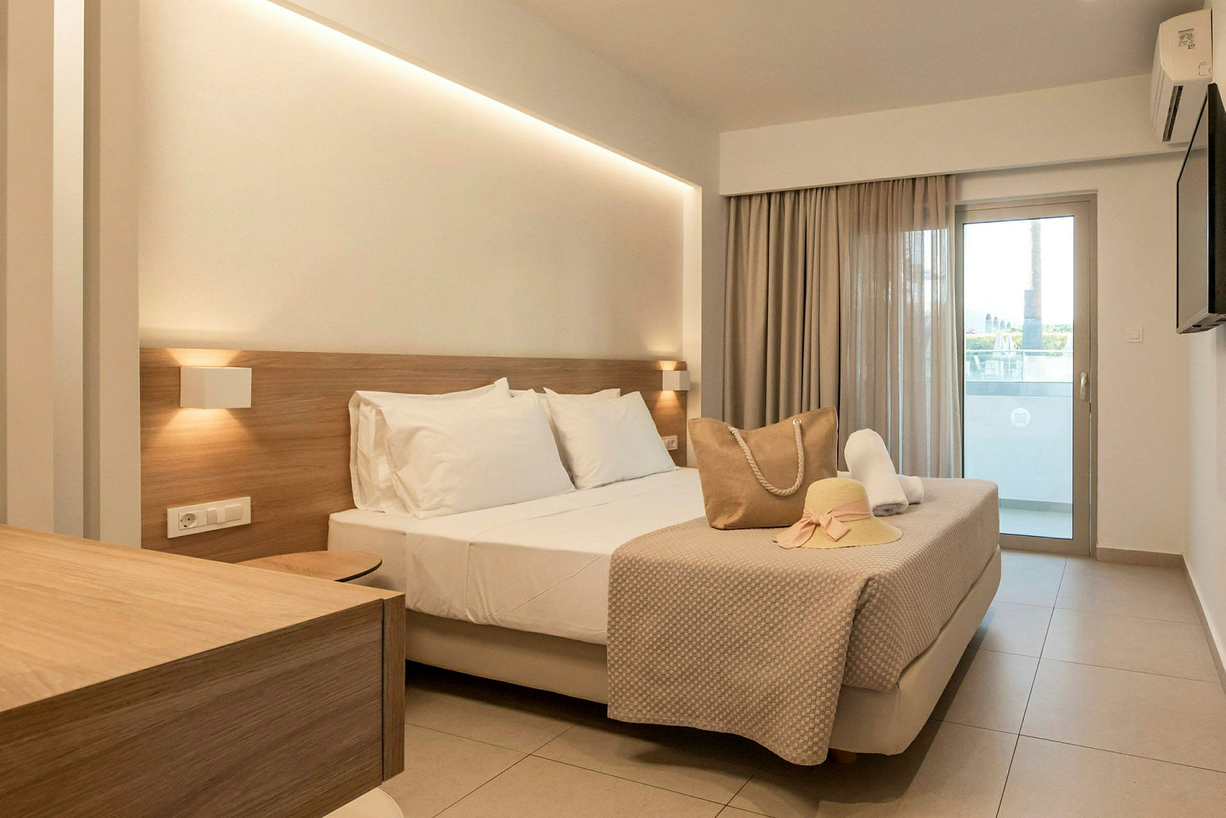 Modernt hotellrum med en dubbelsäng, beige inredning och en balkong. (AI-genererad text)