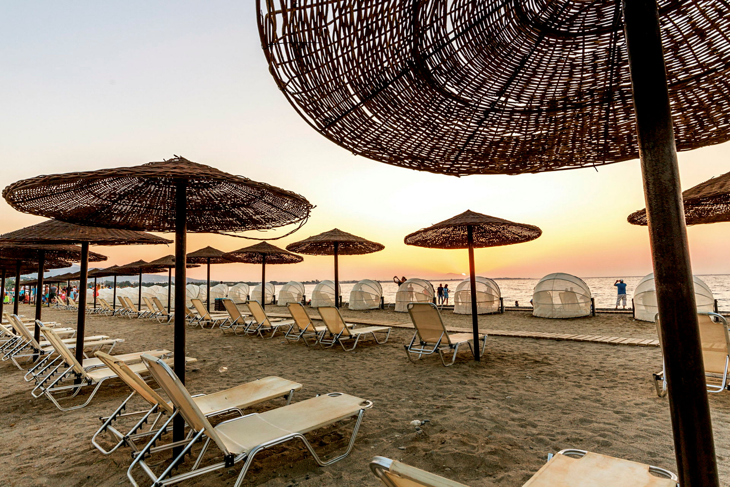 Strand med solstolar och parasoller i skymning. (AI-genererad text)