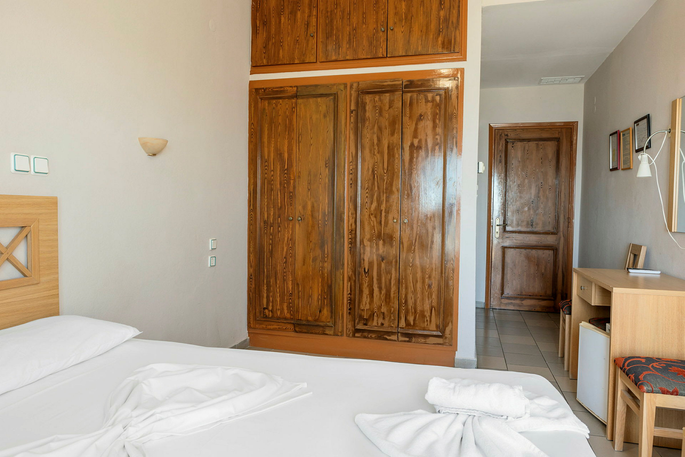 Ett hotellrum med träskåp, en säng och en skrivbordshörna. (AI-genererad text)