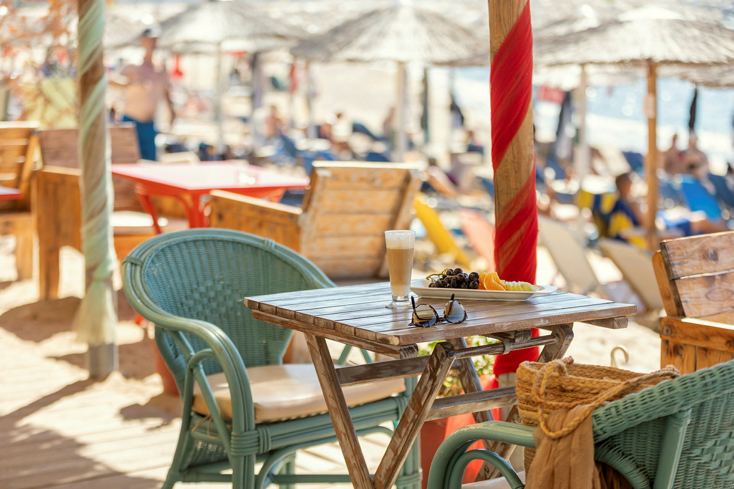 Ett bord med frukt och ett glas dryck, omgiven av stolar vid en strandservering. (AI-genererad text)