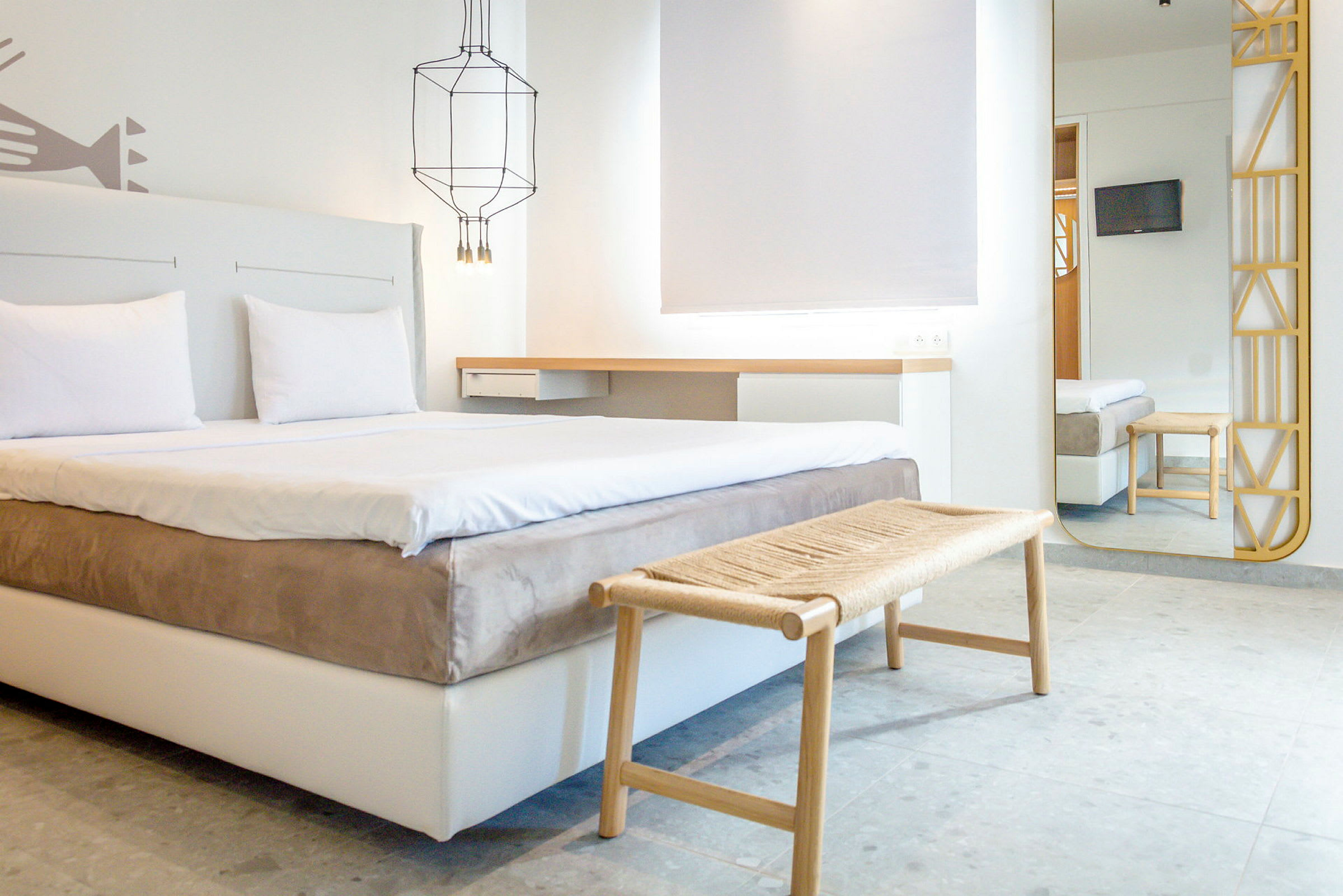 Ett modernt hotellrum med dubbelsäng, sittbänk och väggspegel. (AI-genererad text)