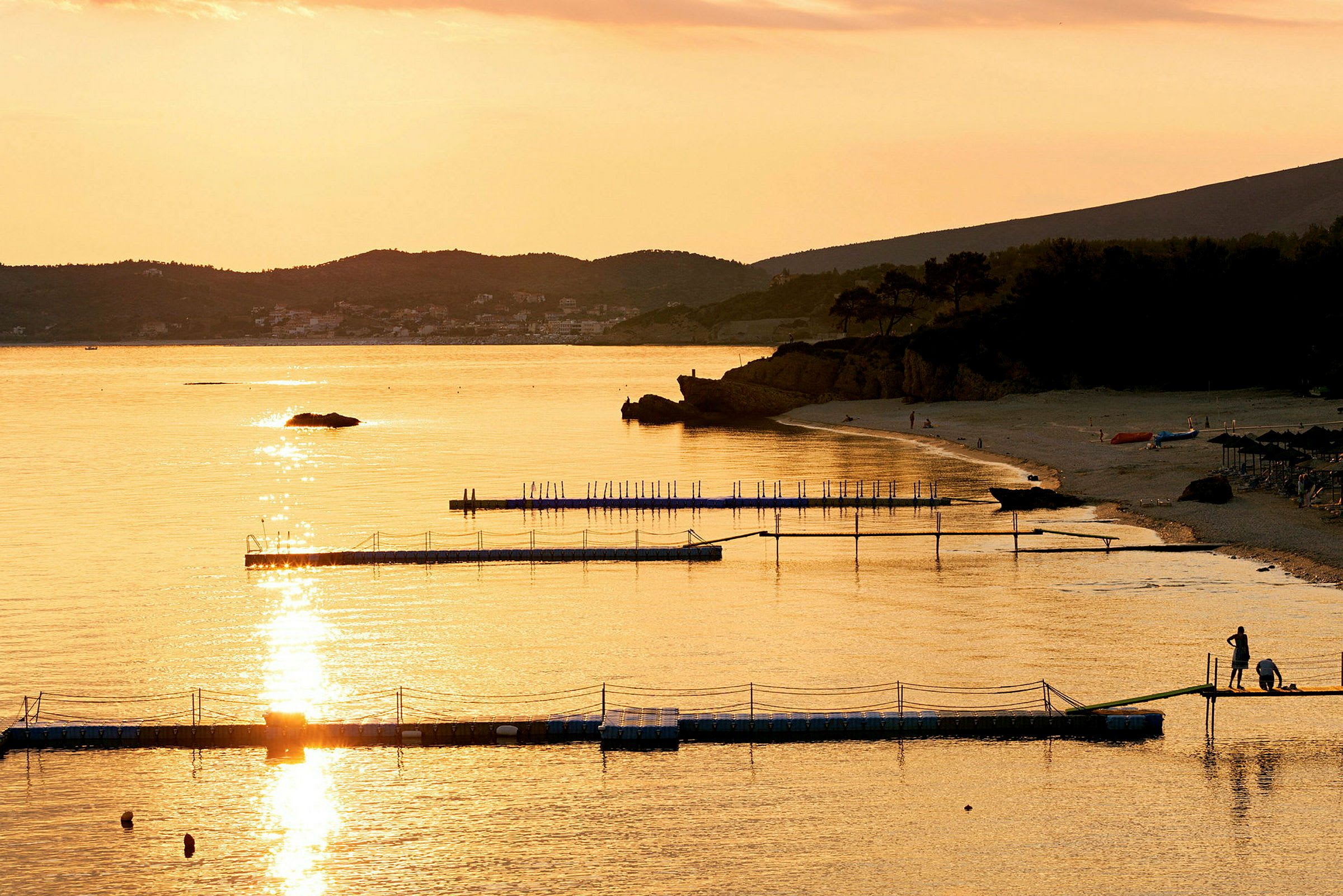En strand vid solnedgång med bryggor i vattnet. (AI-genererad text)