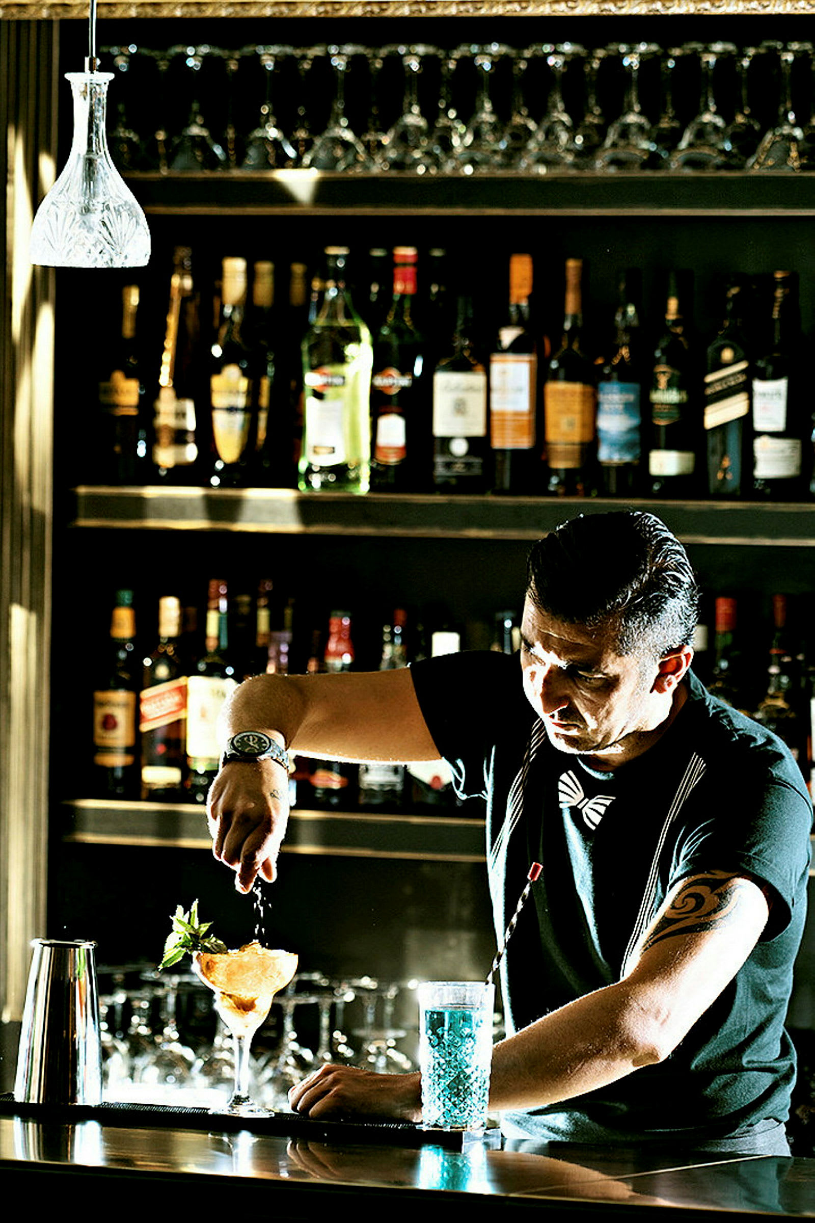 En bartender bereder en cocktail på en bardisk, med flaskor och glas i bakgrunden. (AI-genererad text)