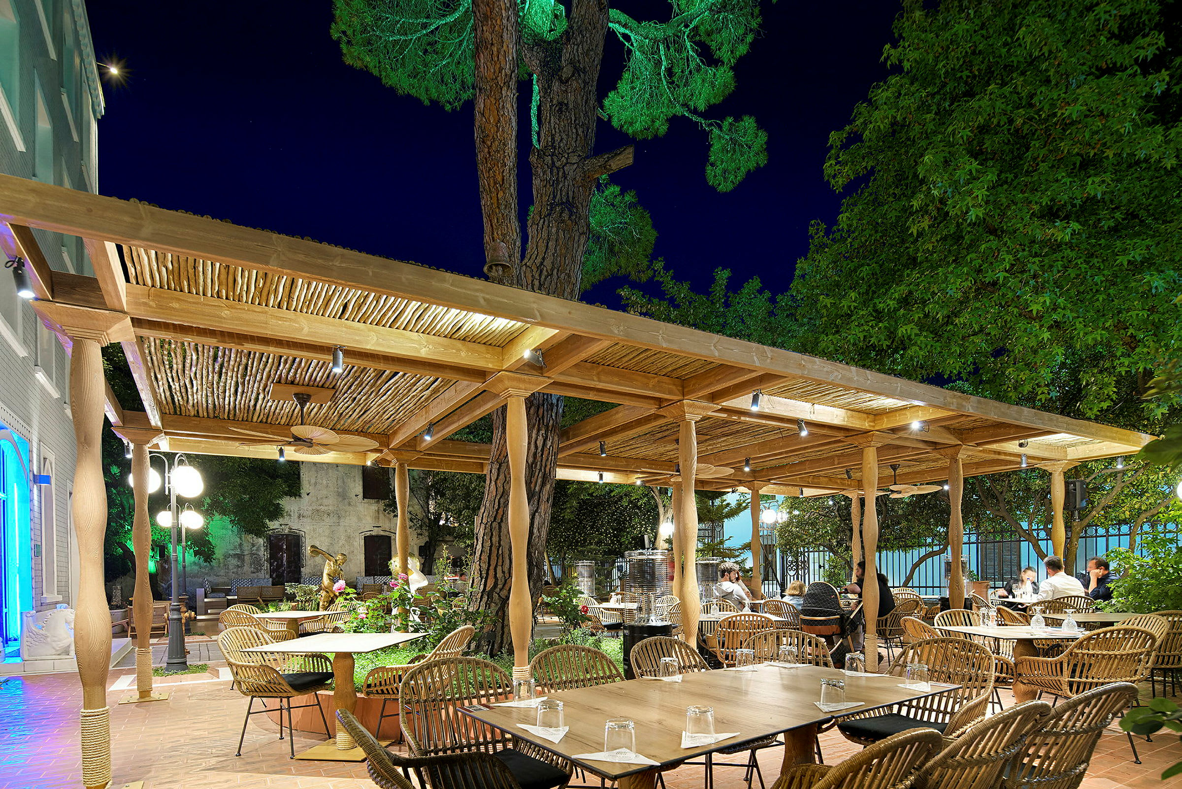 En utomhusrestaurang med träpergola och bord under natten. (AI-genererad text)