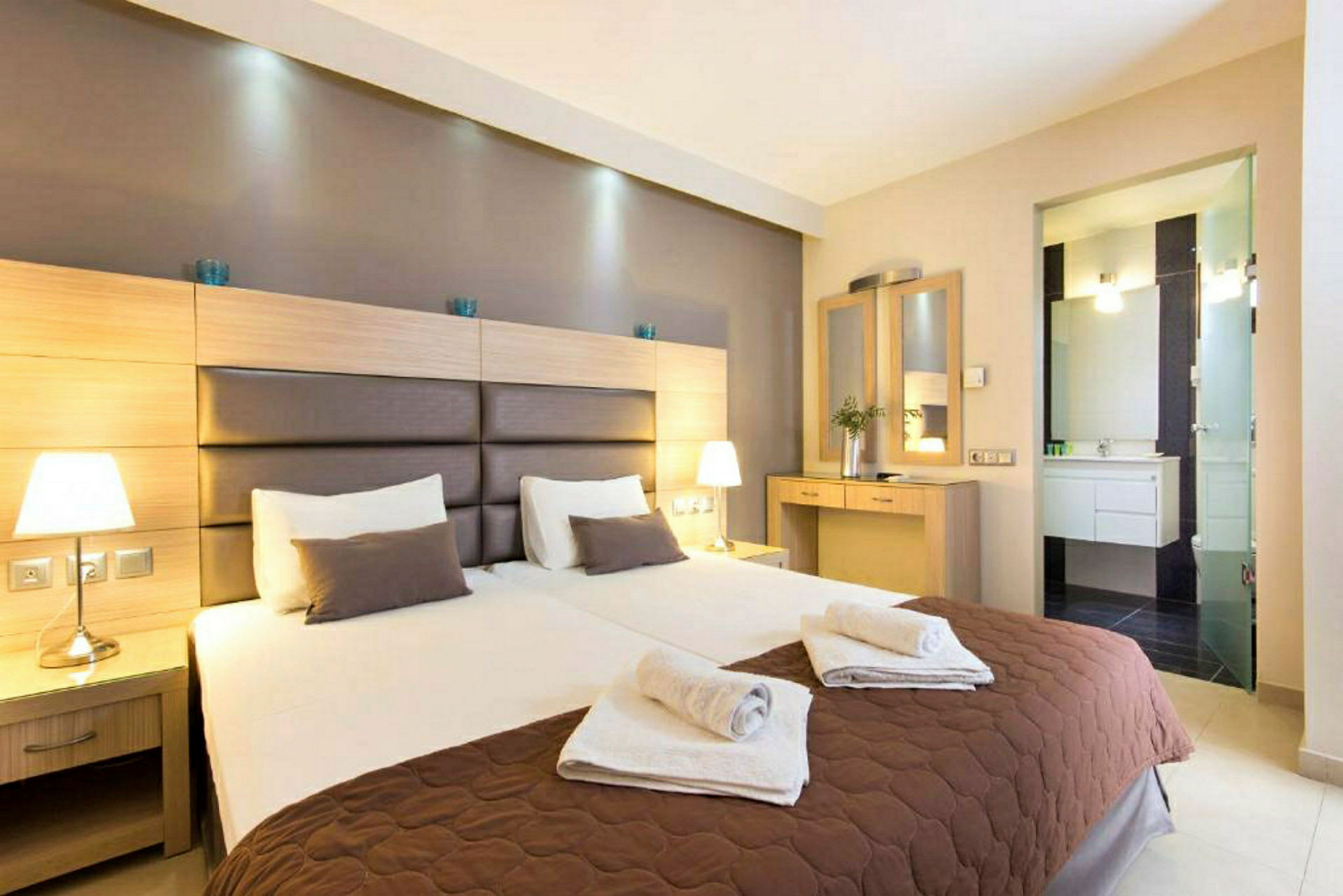Två bäddade enkelsängar i ett hotellrum med nattduksbord och spegel. (AI-genererad text)