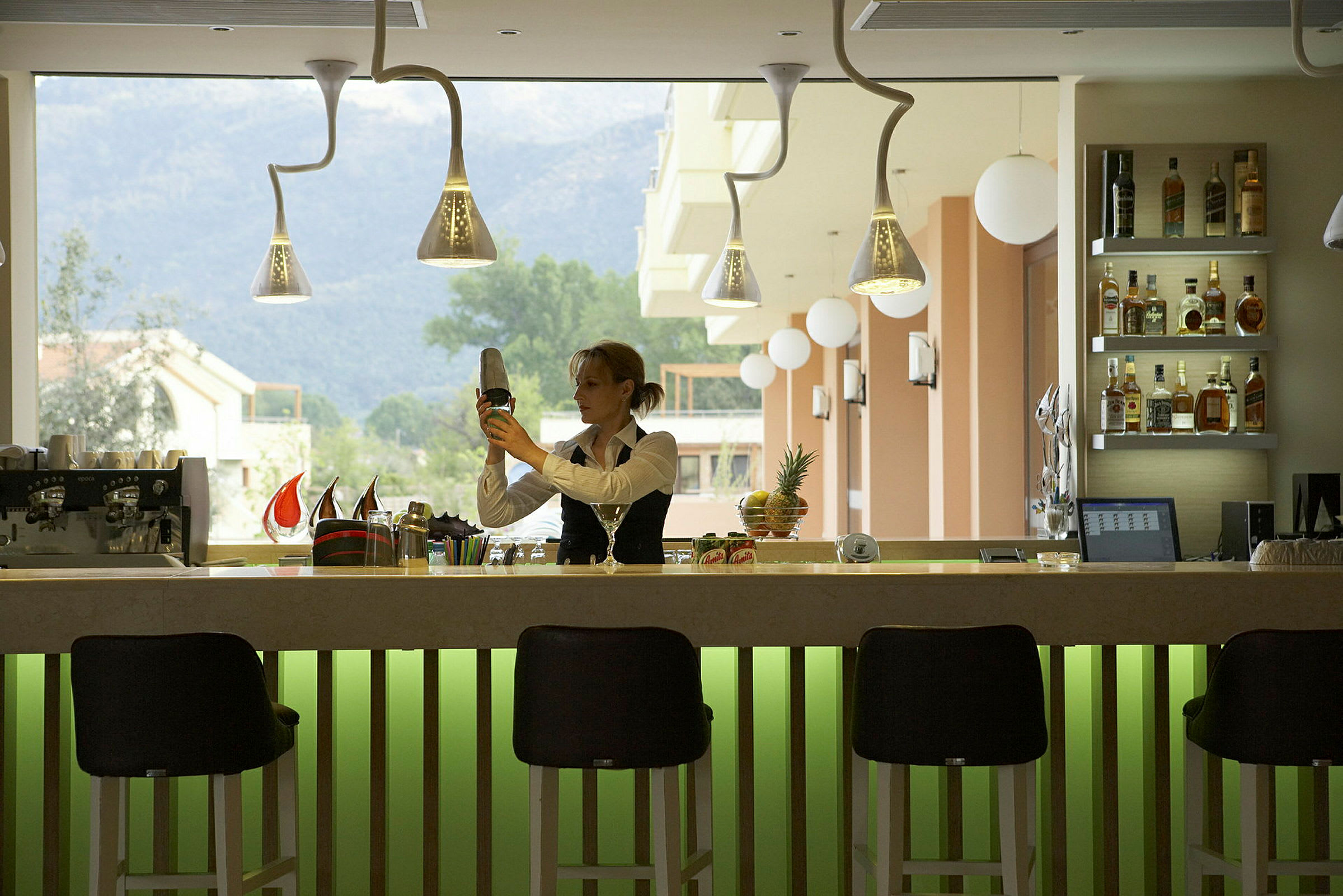 En bartender förbereder en drink vid en bar med en ljusgrön front. (AI-genererad text)
