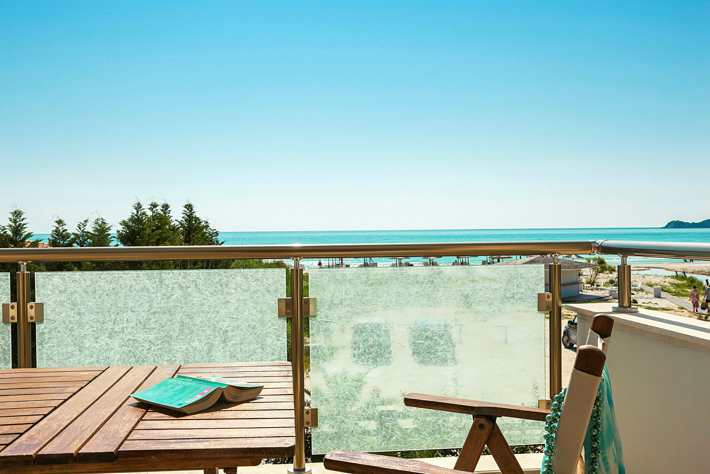 En balkong med bord och stol, med utsikt över havet och en klarblå himmel. (AI-genererad text)