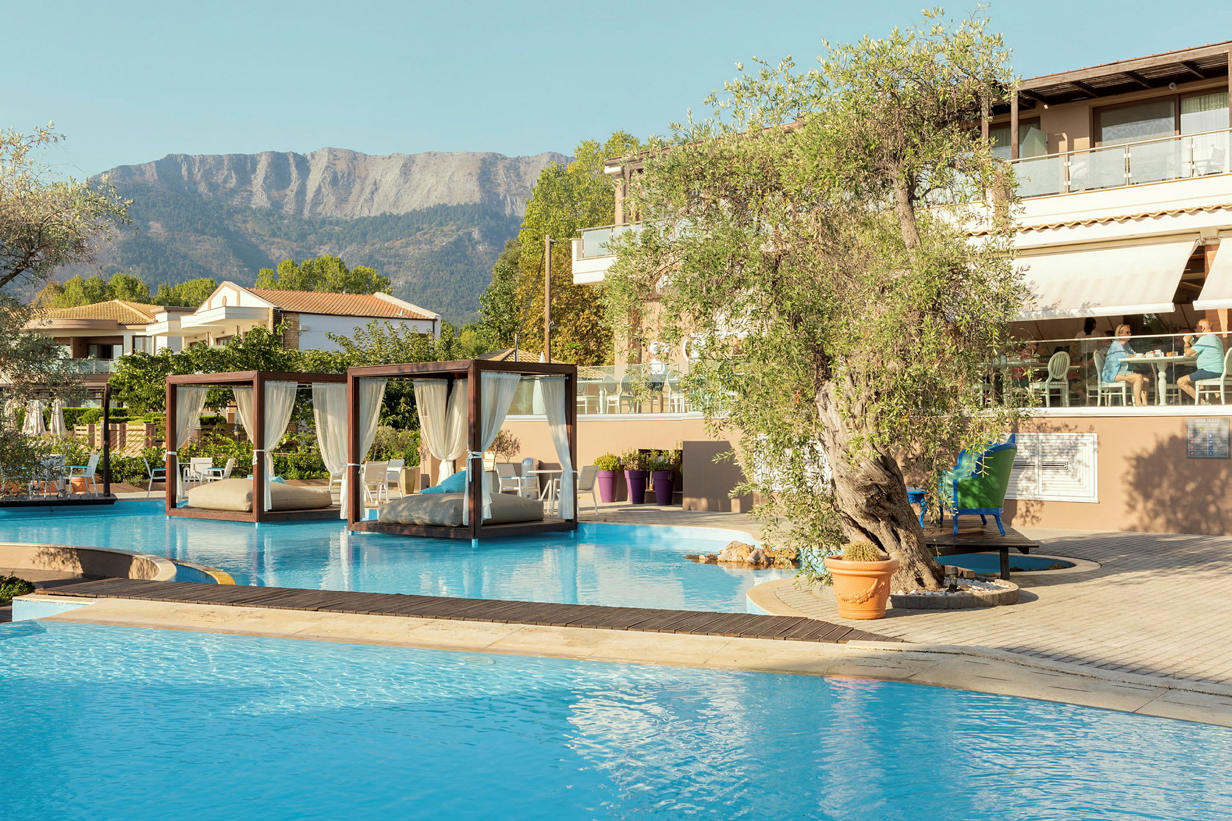En pool med balinesiska dagbäddar och ett hotell med sittområde i bakgrunden. (AI-genererad text)