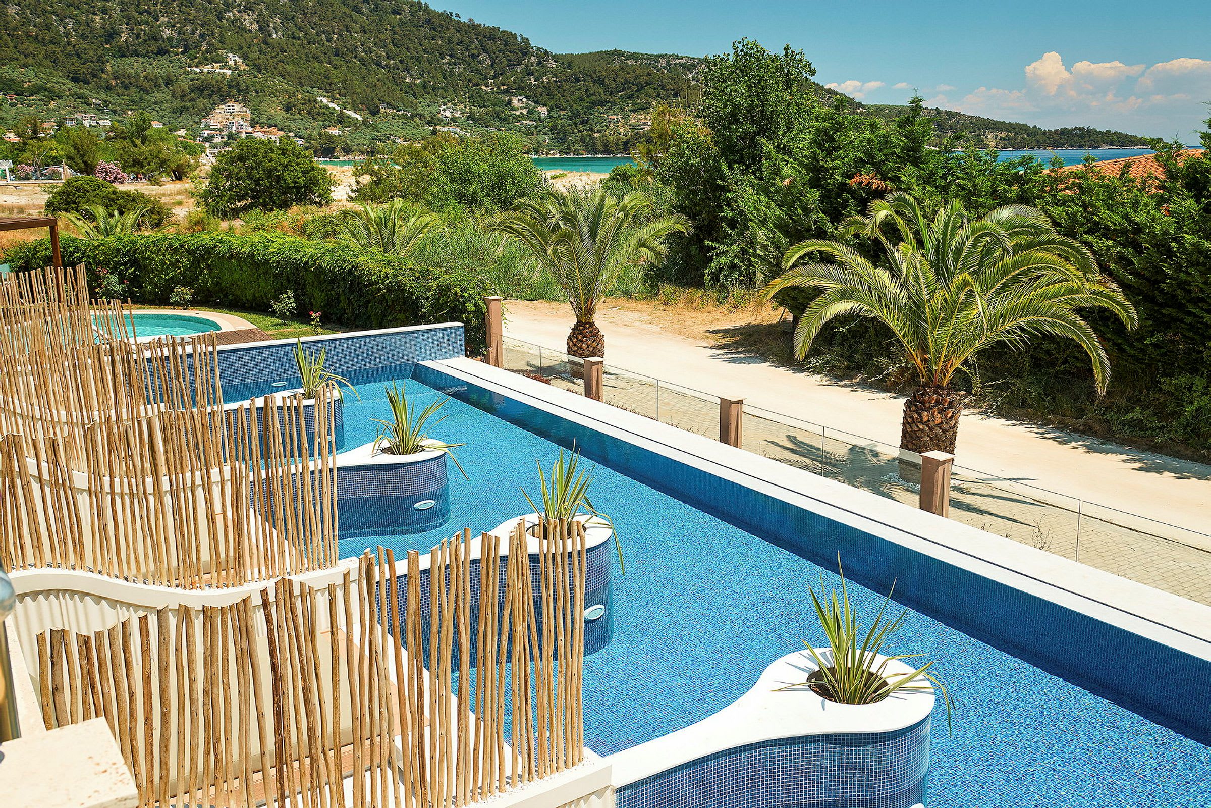 Pool med blått vatten, växtdekorationer och omgivande grönska. (AI-genererad text)