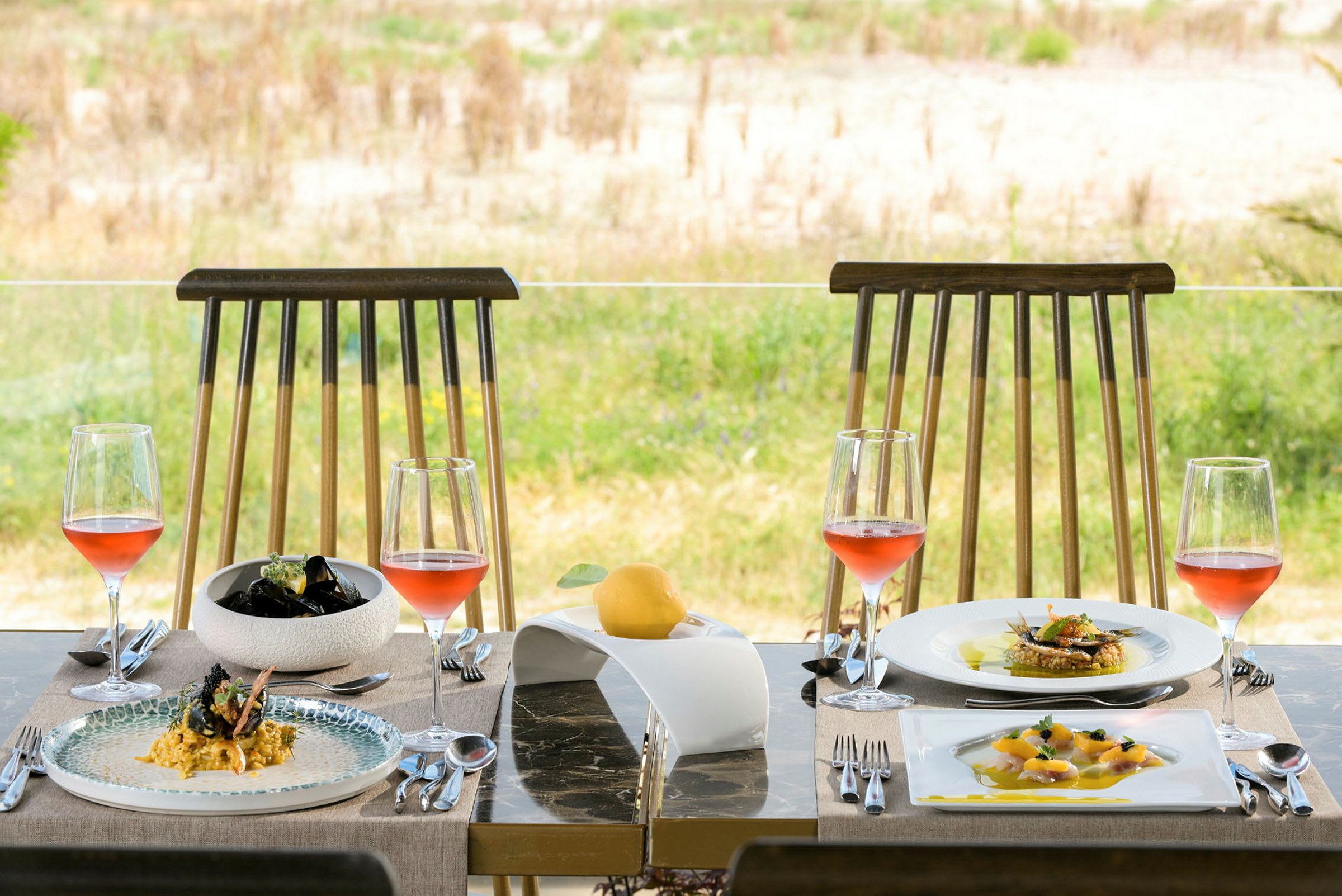 Ett dukat bord med två stolar, mat och glas med rosévin. (AI-genererad text)